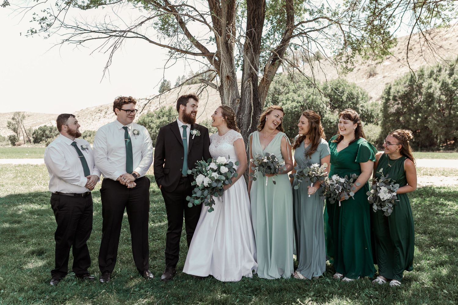 Wedding party lined up for formal photo with mix of green and mint colored dresses.