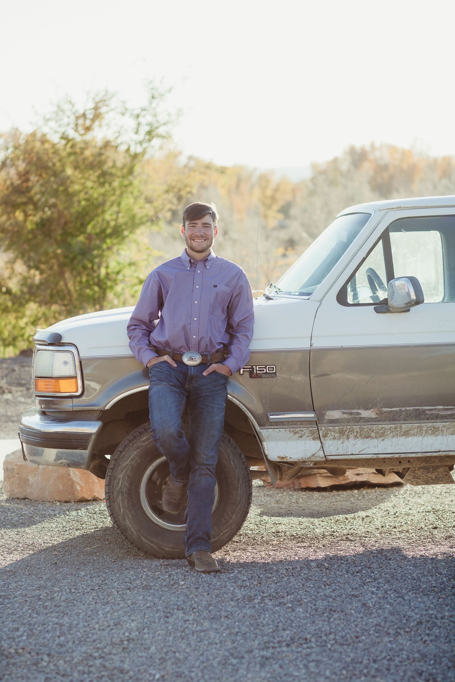 Casual portrait of someone leaning against a vintage Ford F150 pickup truck on a sunny autumn day.