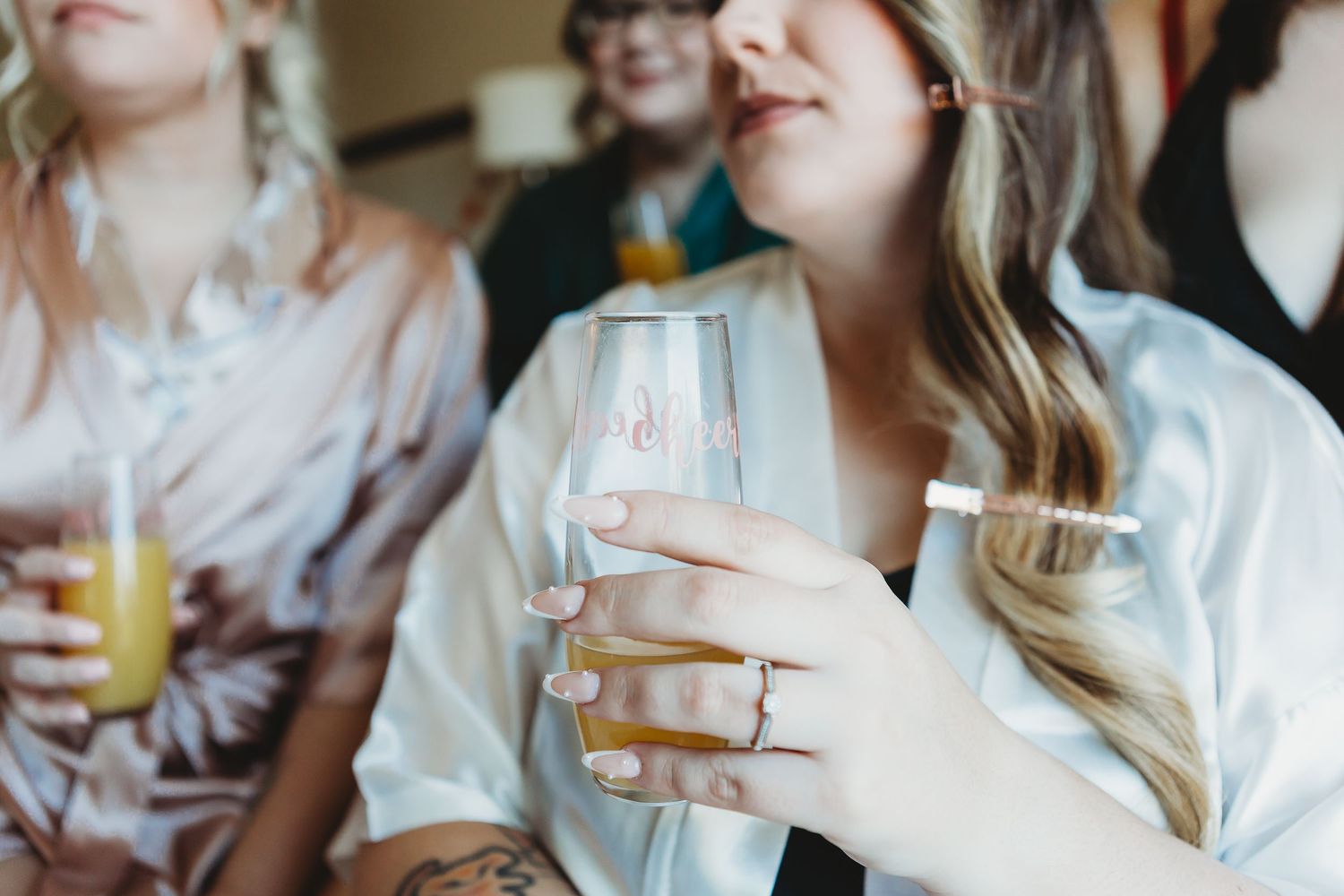 Wedding party members hold champagne glasses during pre-ceremony celebration.