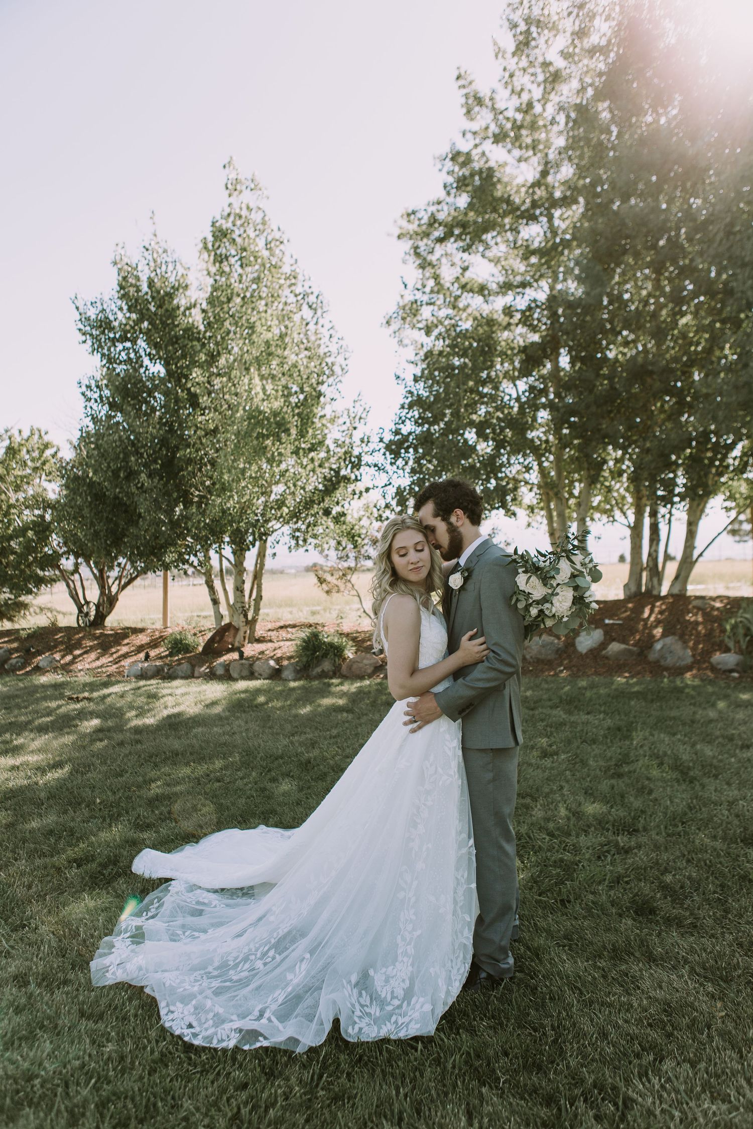Ethereal wedding photography with sunlit trees and flowing lace dress details.