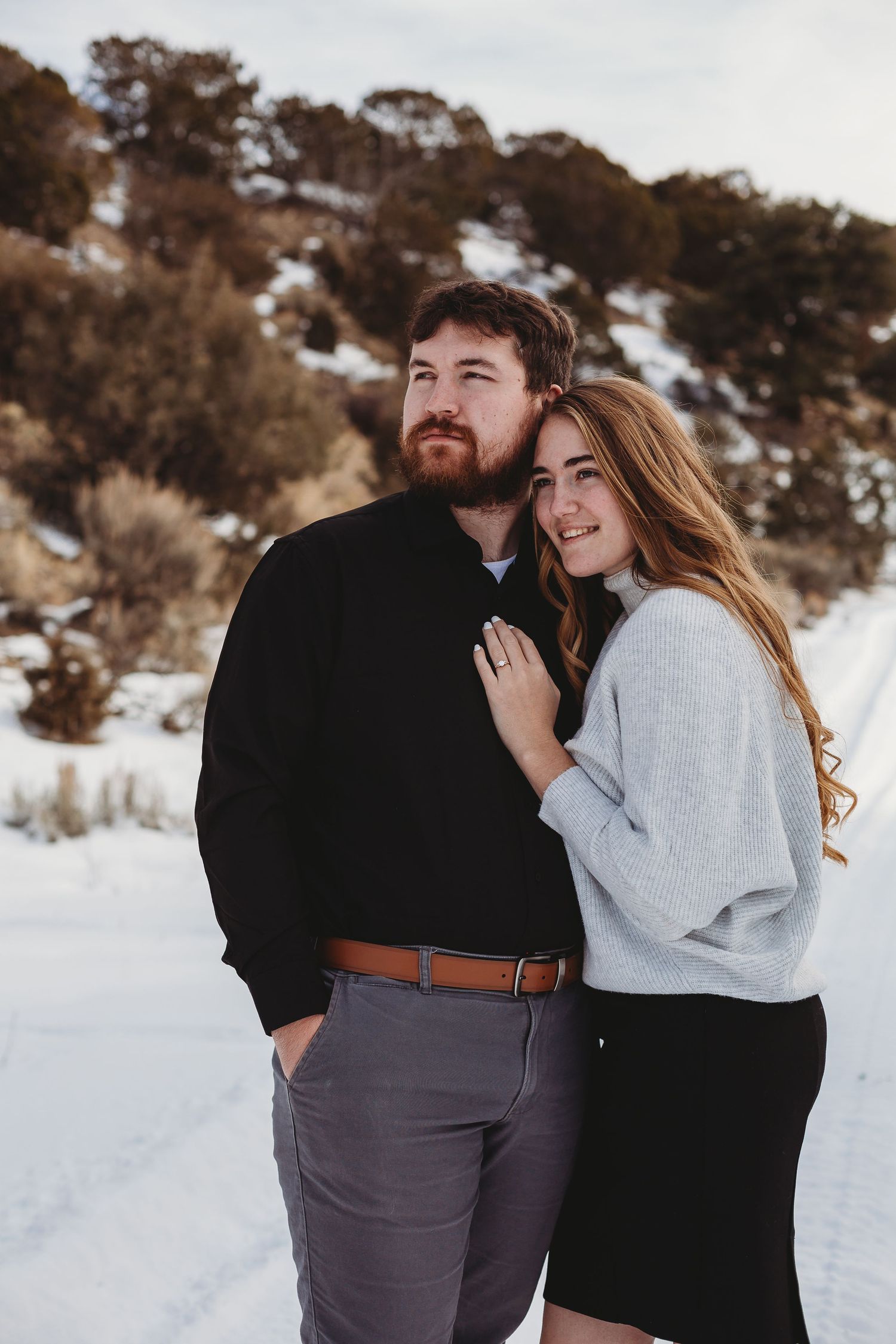 Intimate couple's portrait with gentle smiles against a winter mountain landscape.