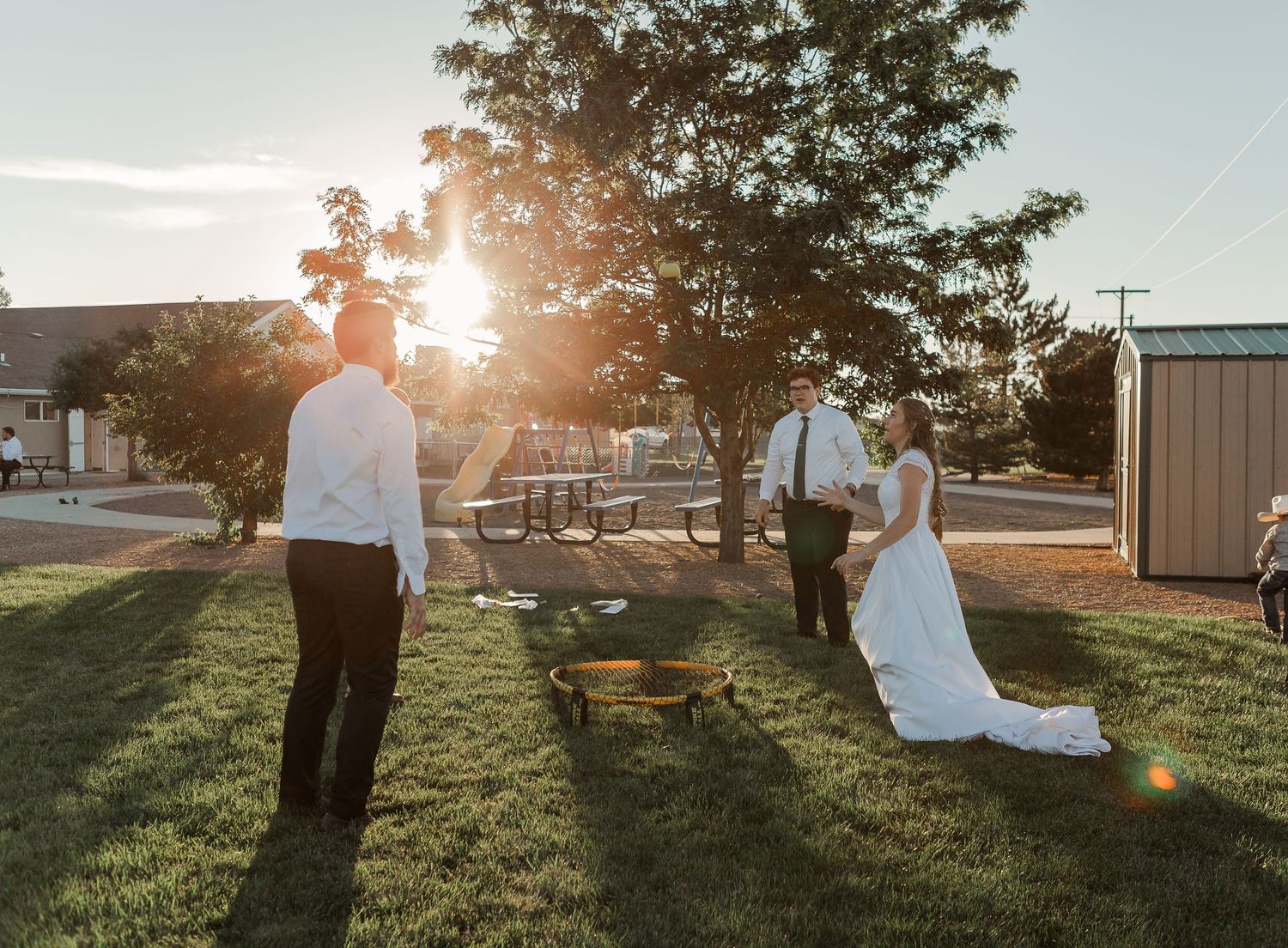 Sunset wedding photo with lens flare in an outdoor garden setting.