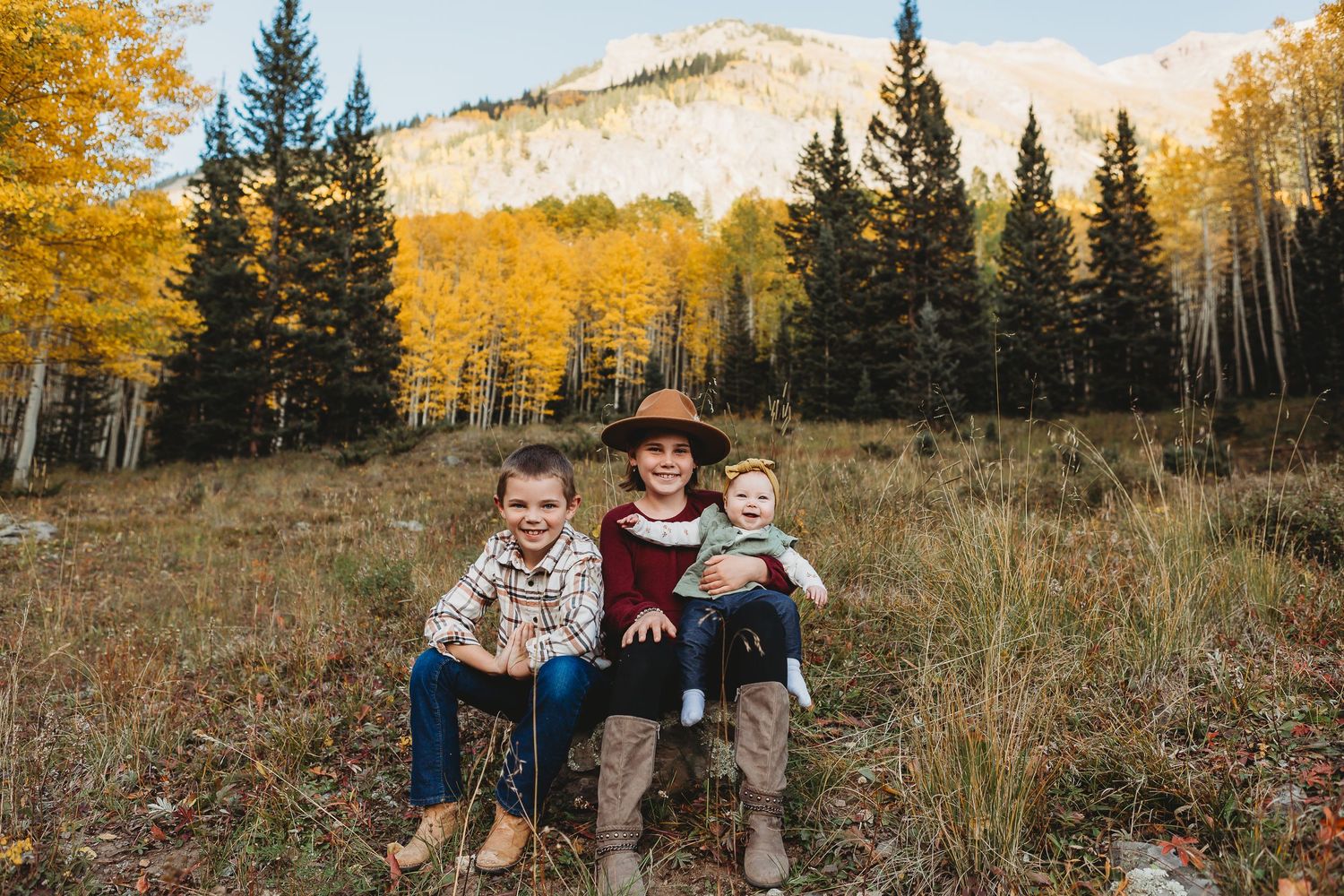 People sitting on rocks with beautiful fall foliage and mountains in the background.