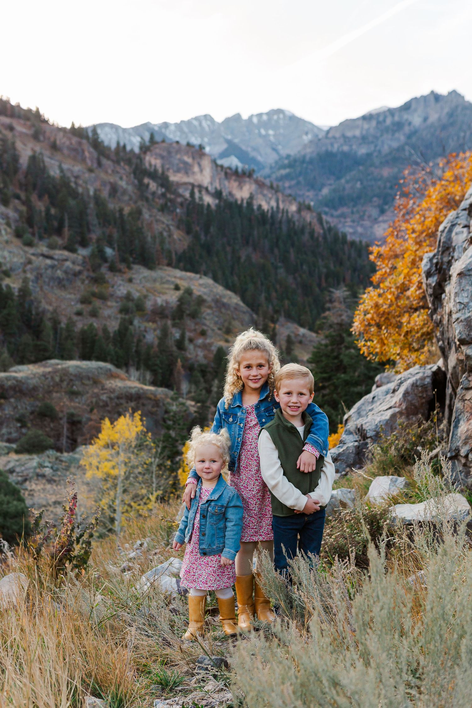 Group poses outdoors in fall against beautiful mountain landscape with evergreen forests.