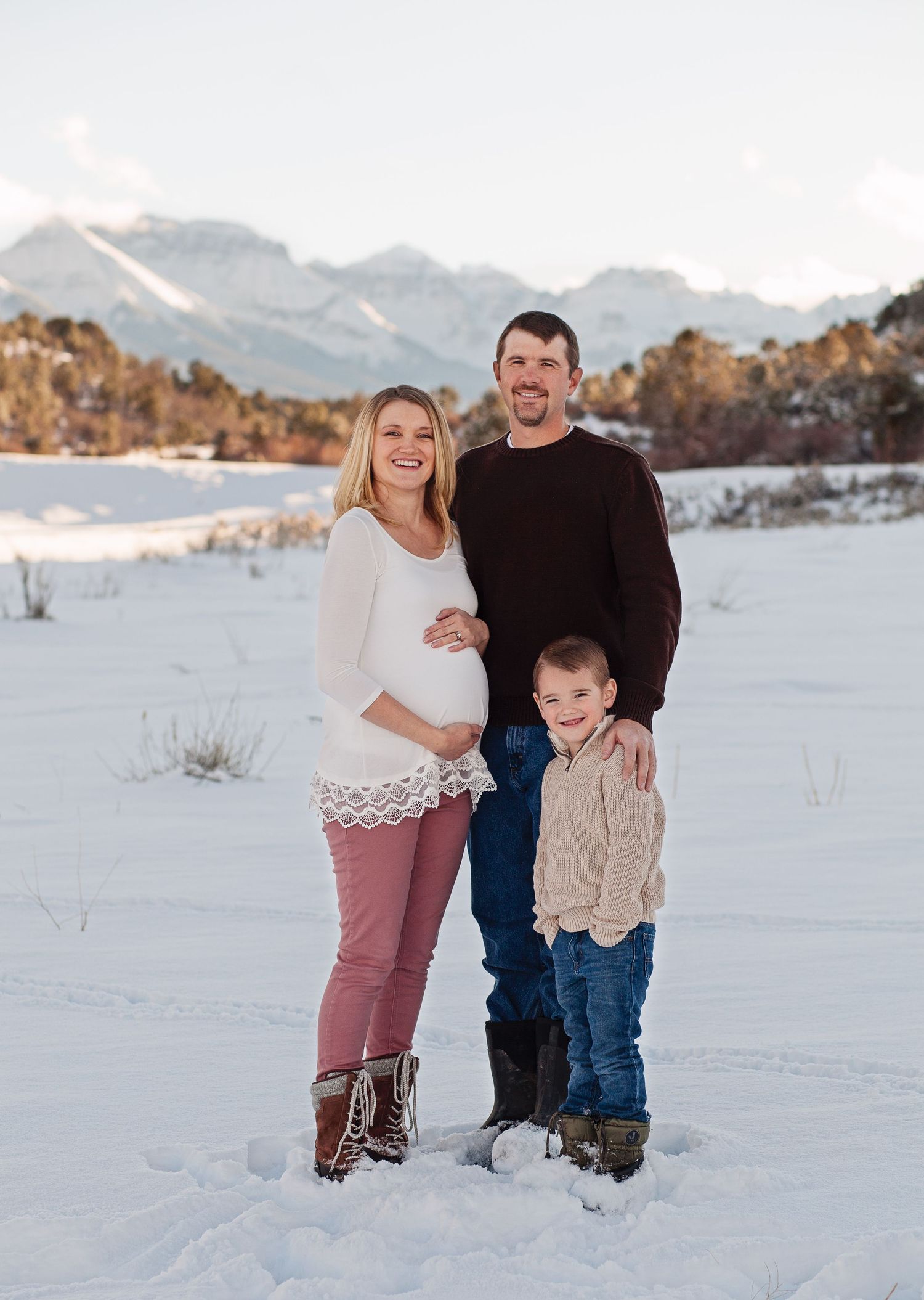 Winter family portrait with snowy mountains in background.