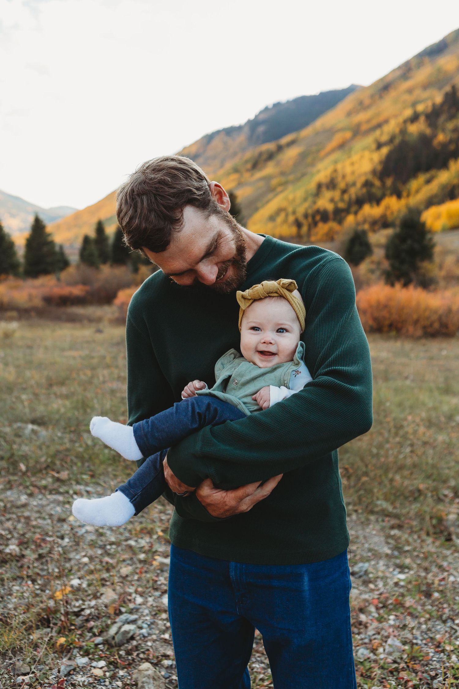 A tender moment between parent and baby against a backdrop of autumn mountains in Colorado.