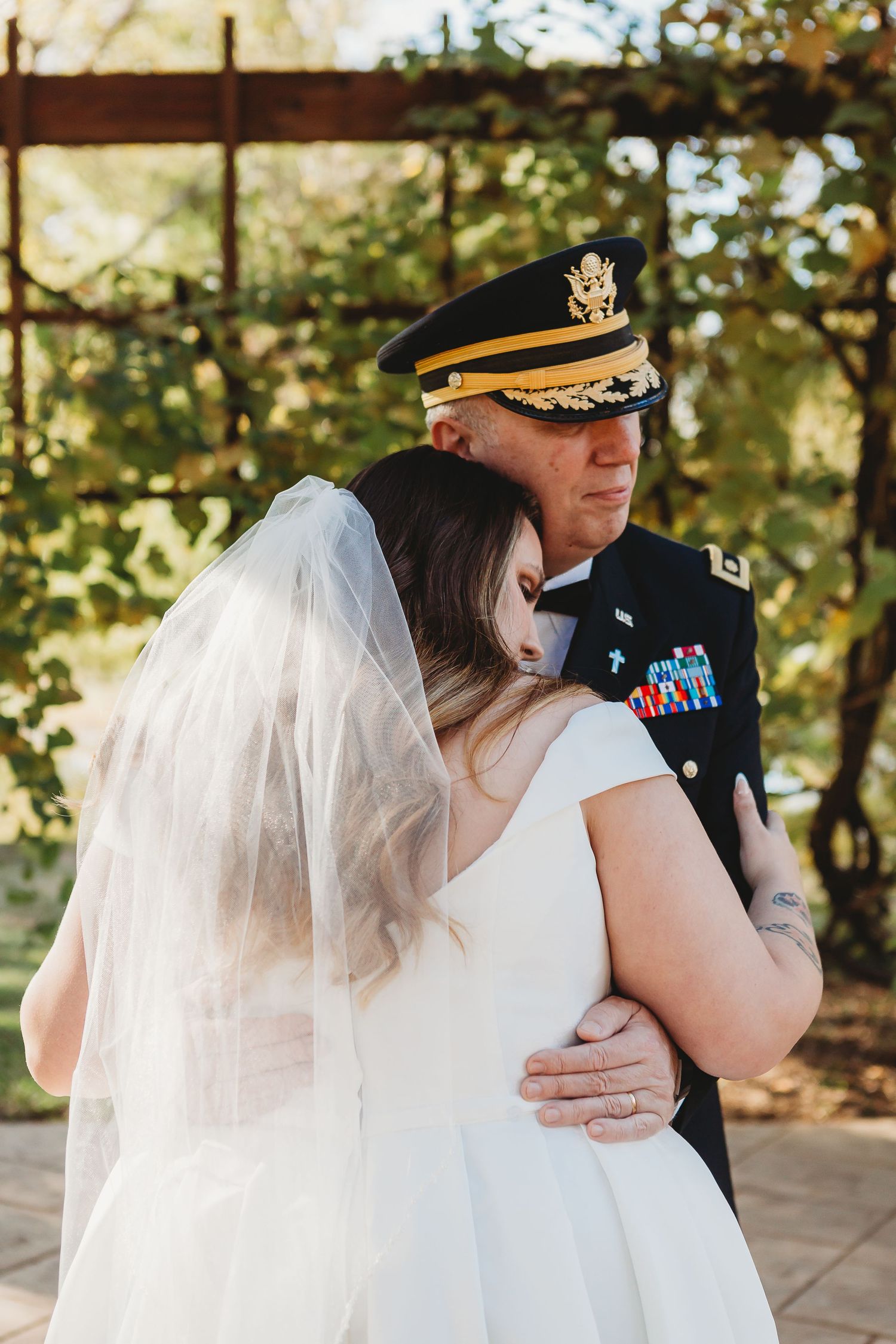 Military wedding couple embraces during intimate moment at outdoor ceremony venue.