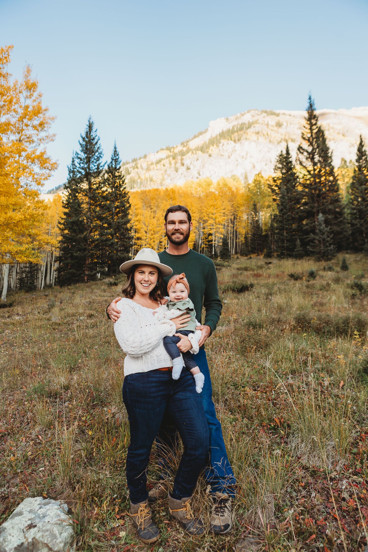 Scenic mountain landscape with golden aspen trees frames an outdoor portrait.