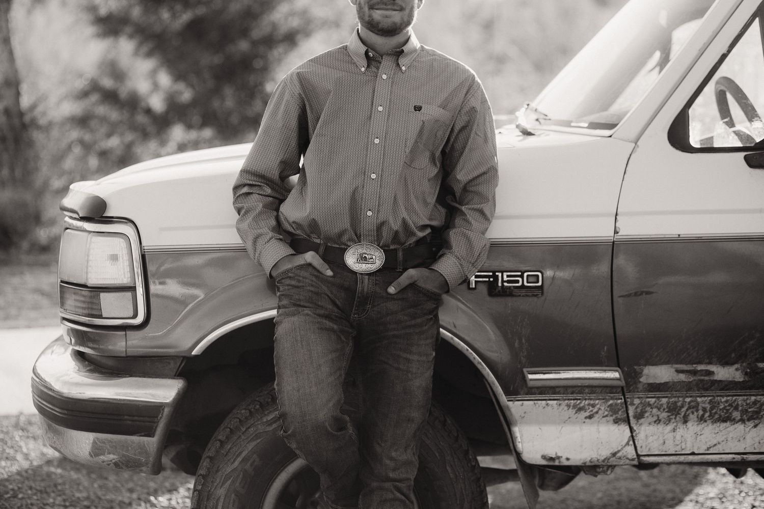 Black and white portrait of someone posing next to a Ford F150 truck.