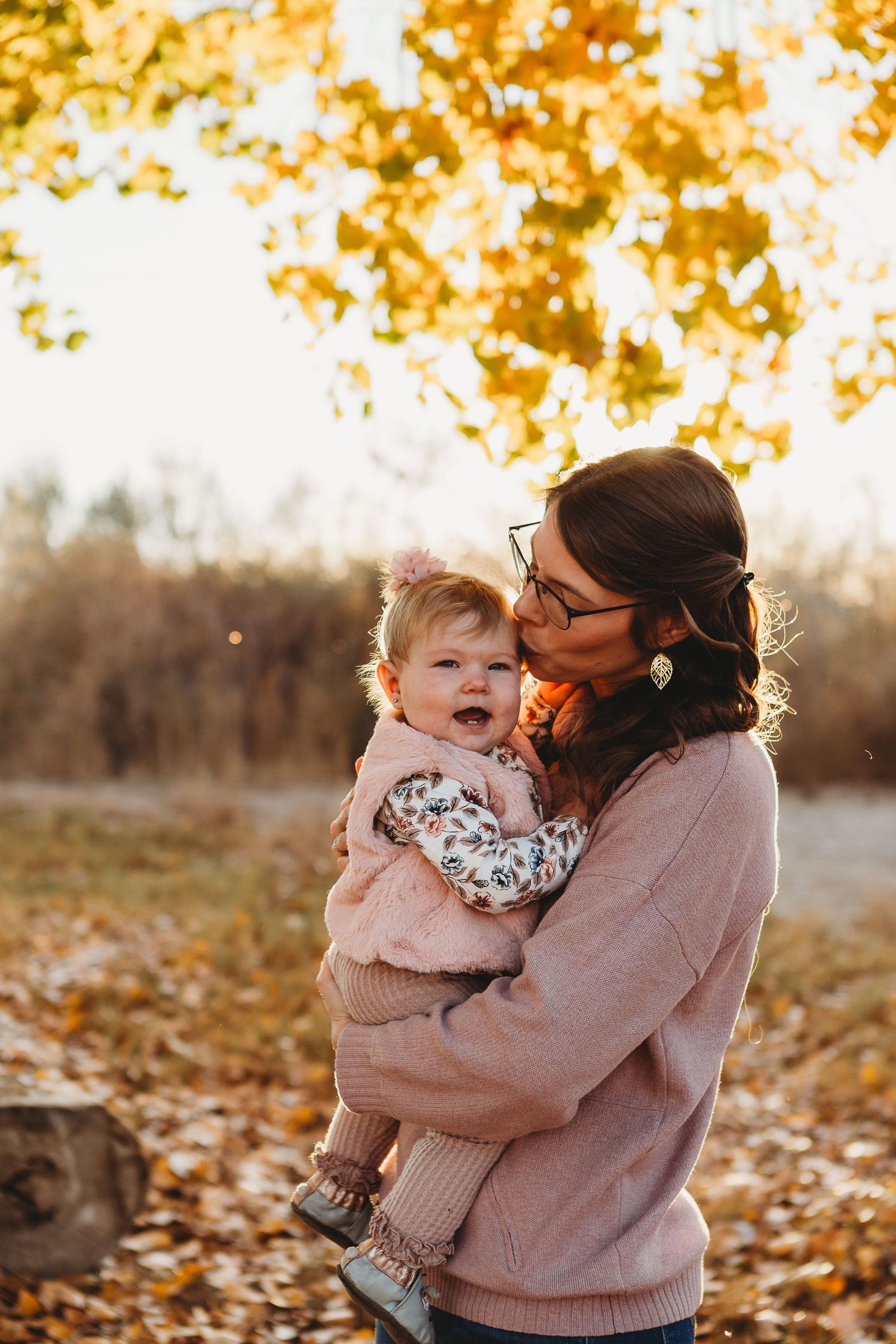 Sweet moment shared between two people in pink sweaters amid fall foliage.