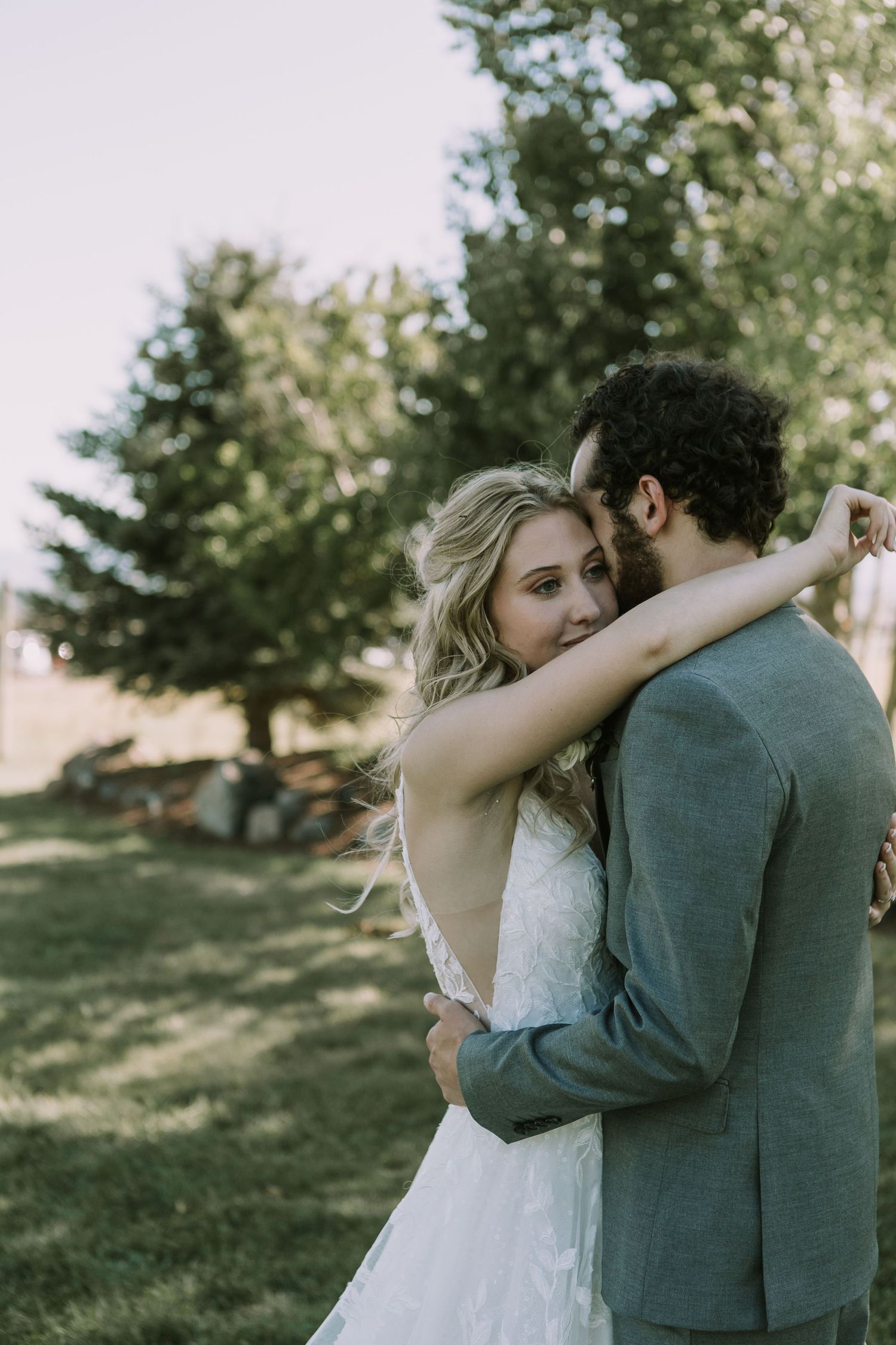 Intimate embrace captured during outdoor wedding photoshoot with soft natural lighting.