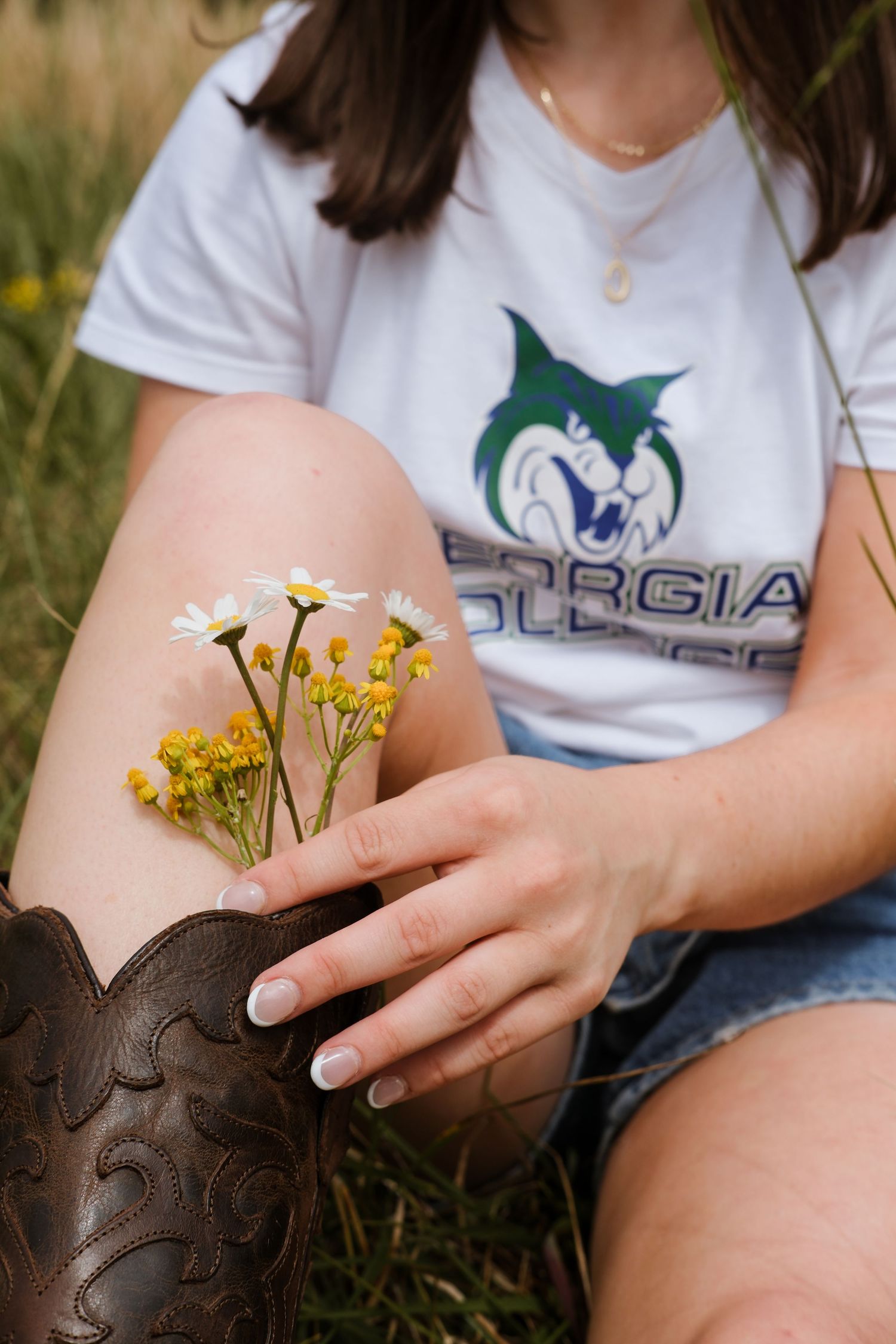 Close-up of wildflowers tucked into a brown cowboy boot in a grassy field.