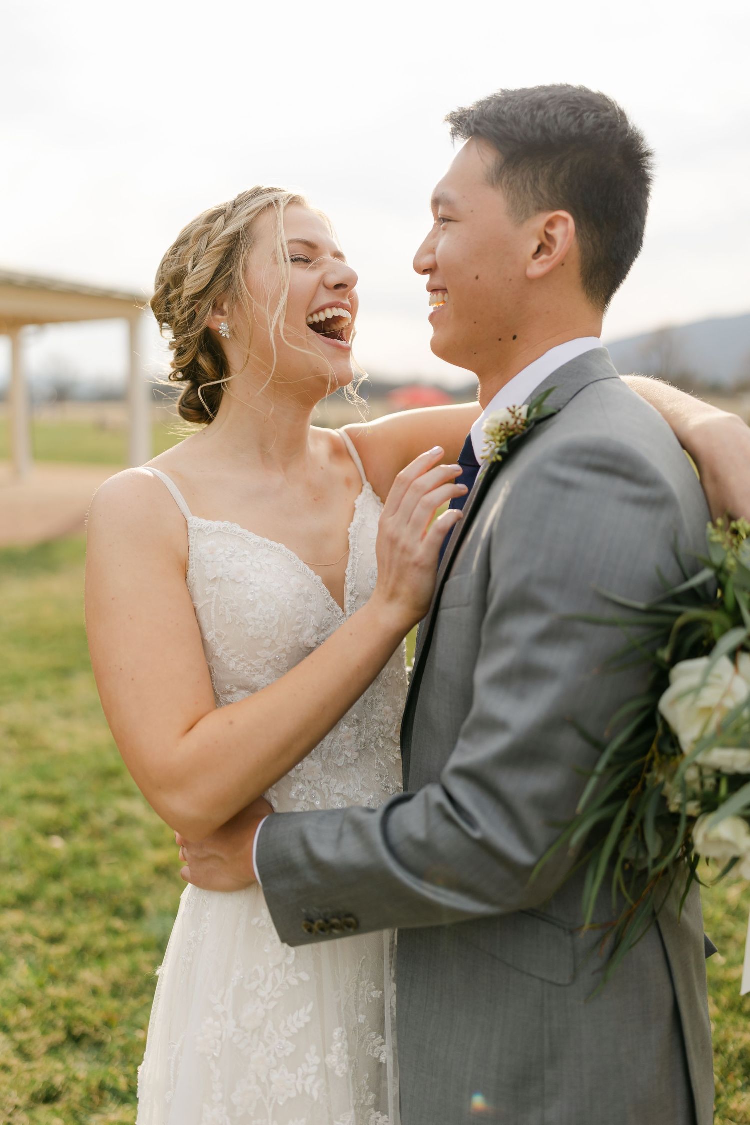 A couple shares laughter and embraces during their outdoor wedding photoshoot.