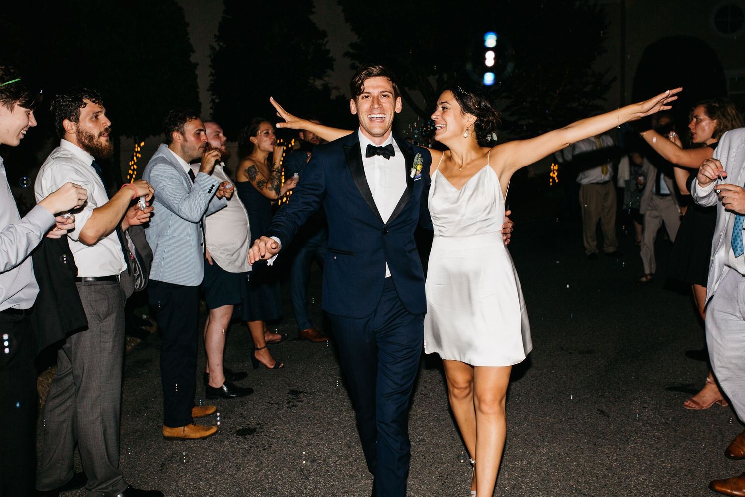 Wedding guests dance and celebrate together on a dark dance floor during an evening reception celebration.