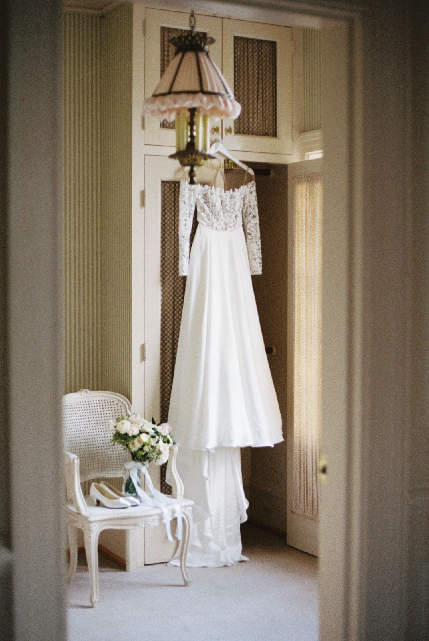 Elegant white wedding dress and accessories displayed in luxurious dressing room.