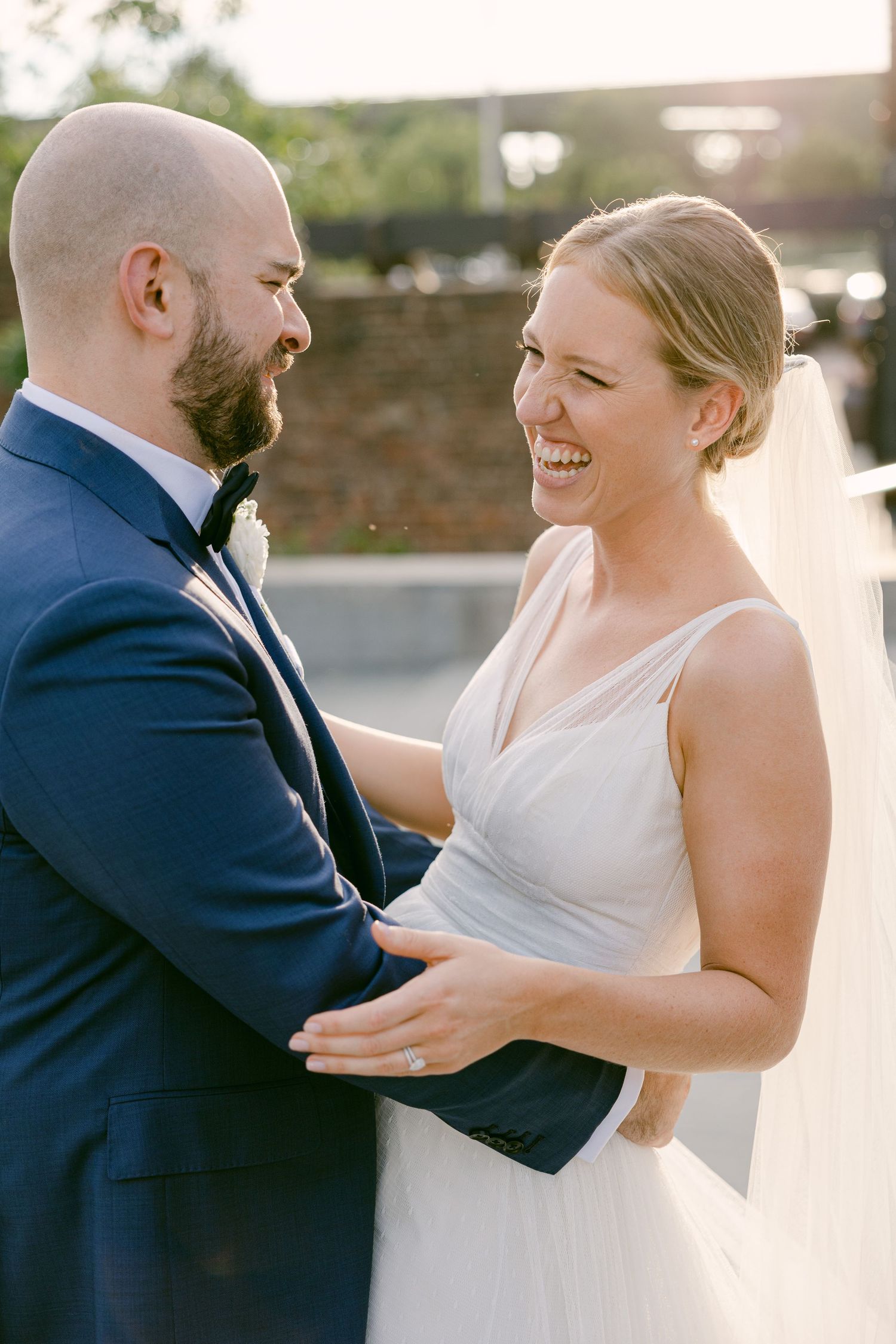 A joyful wedding couple shares a candid moment together at sunset.