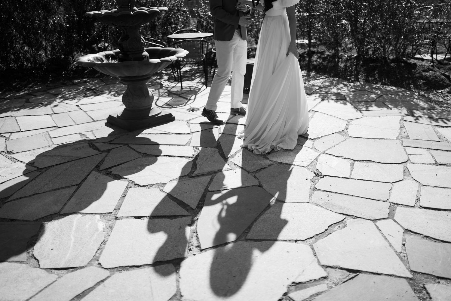 Artistic black and white shadows of wedding party cast on stone pathway.