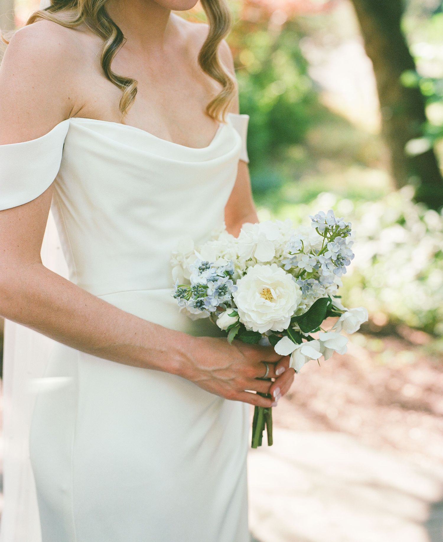 Close-up details of white wedding bouquet and bridal dress in natural sunlight.