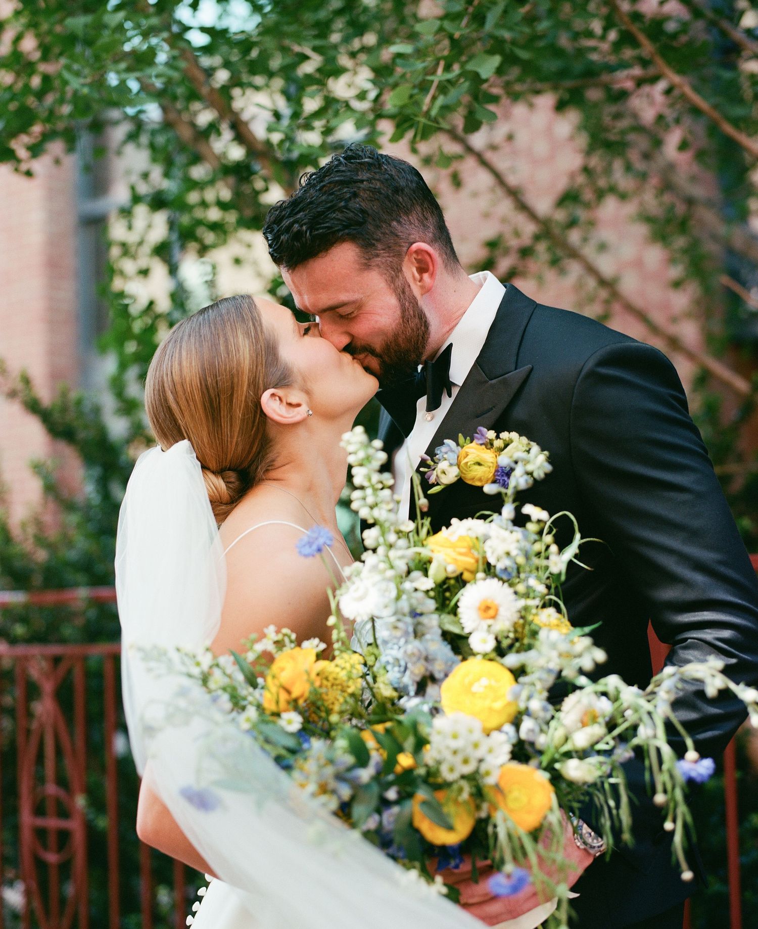 Romantic wedding couple sharing intimate moments with yellow and white bouquet.
