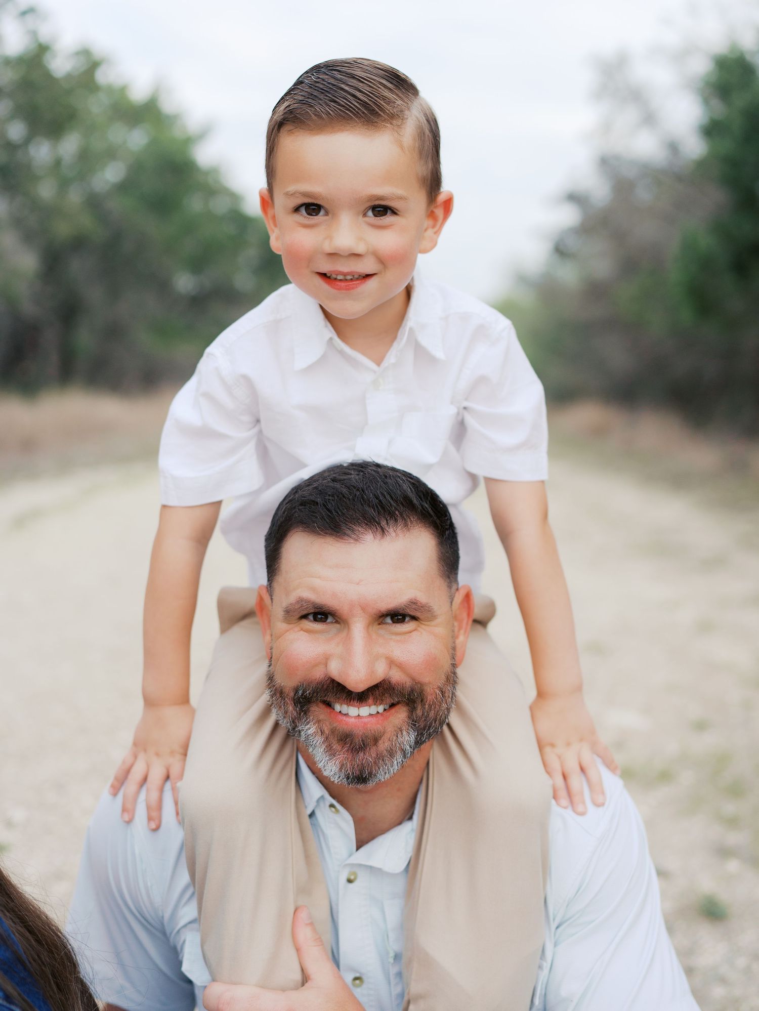 Father carrying his young son on his shoulders during an outdoor family photography session in San Antonio