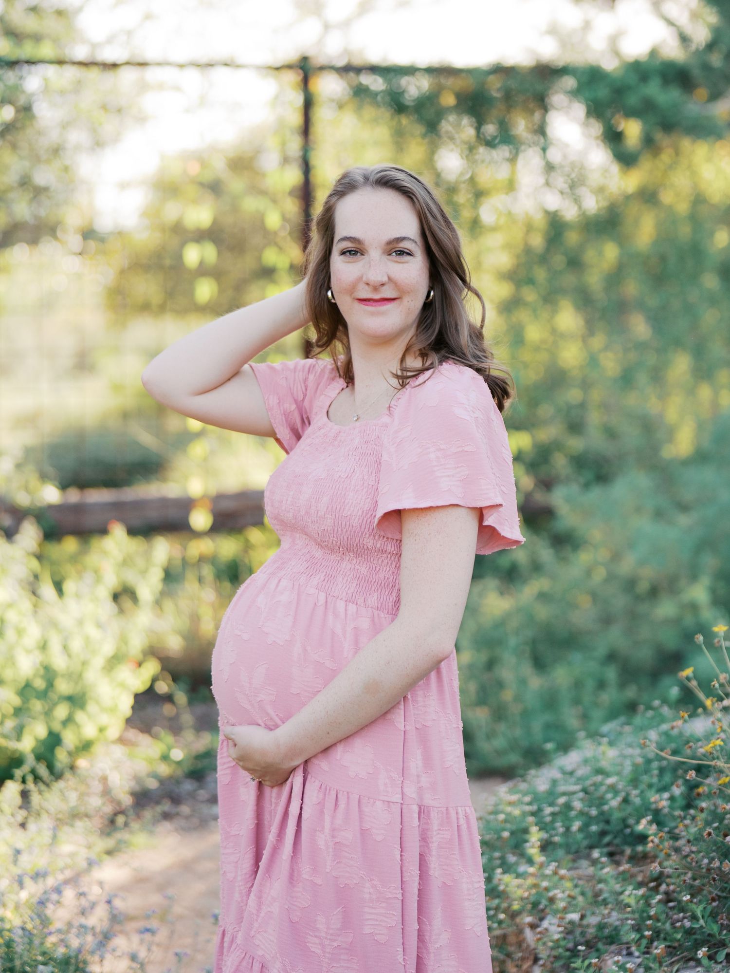 Expecting mother in a pink dress during an outdoor maternity session in San Antonio