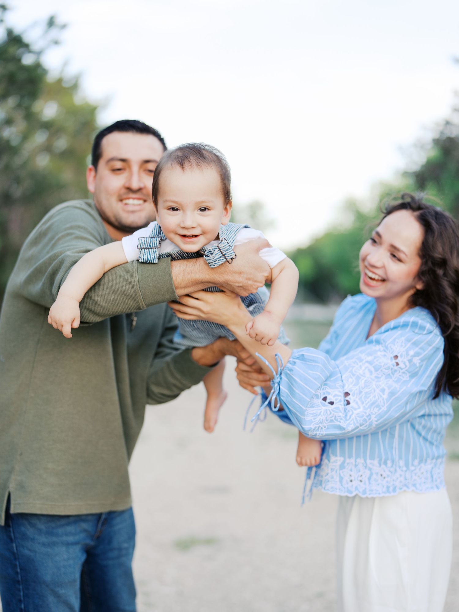 Parents playing with their one year old son during a family photo session at a San Antonio park