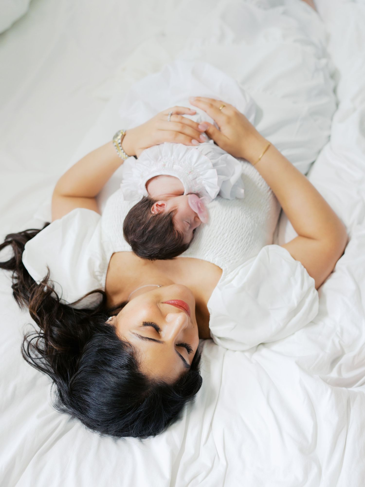 Mother cuddling her newborn baby on a bed during an in home newborn photography session in San Antonio
