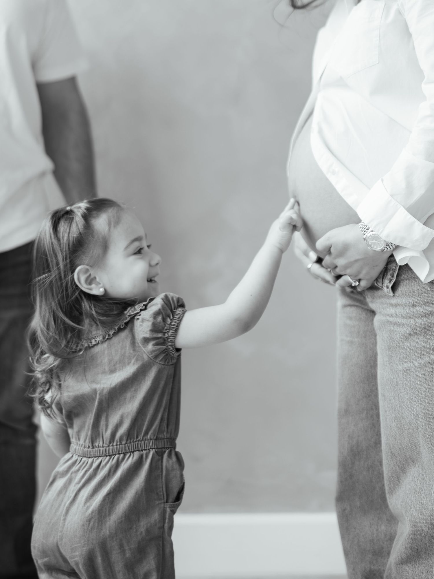 Black and white photo of Toddler touching pregnant mom's belly  during a studio session in san antonio texas.