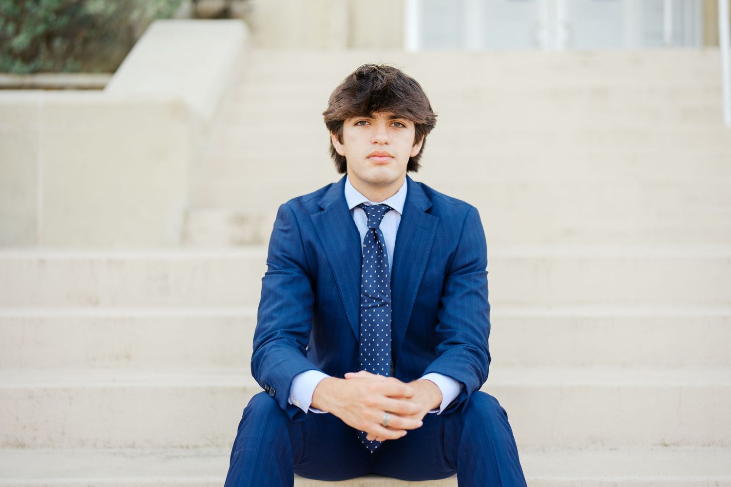 Boy senior graduate sitting on stairs posing for picture.