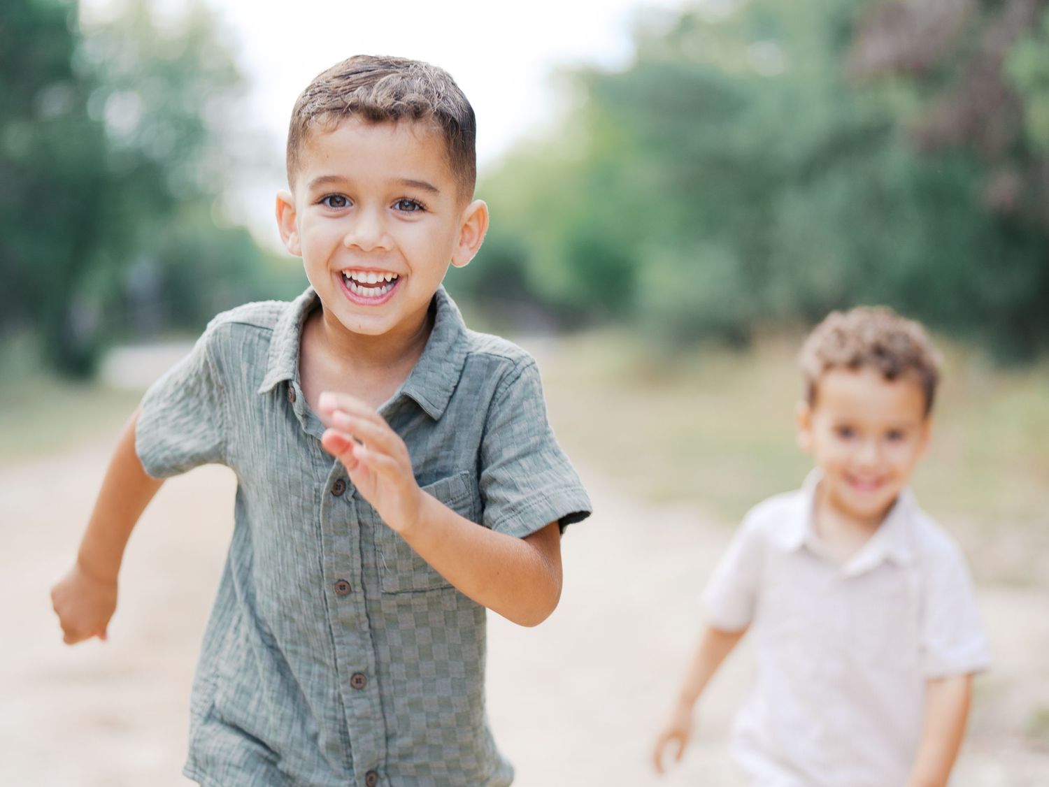 Candid shot of Sibling Boys Playfully running outdoors during a fall family session in San Antonio, Texas