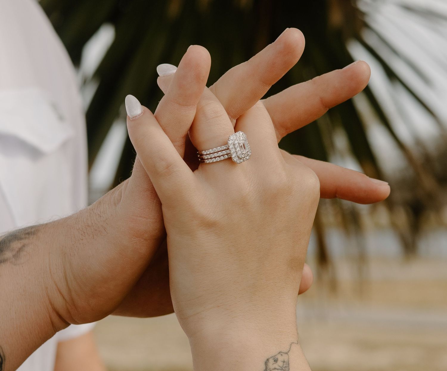 Close-up of hands displaying an elegant diamond engagement ring.