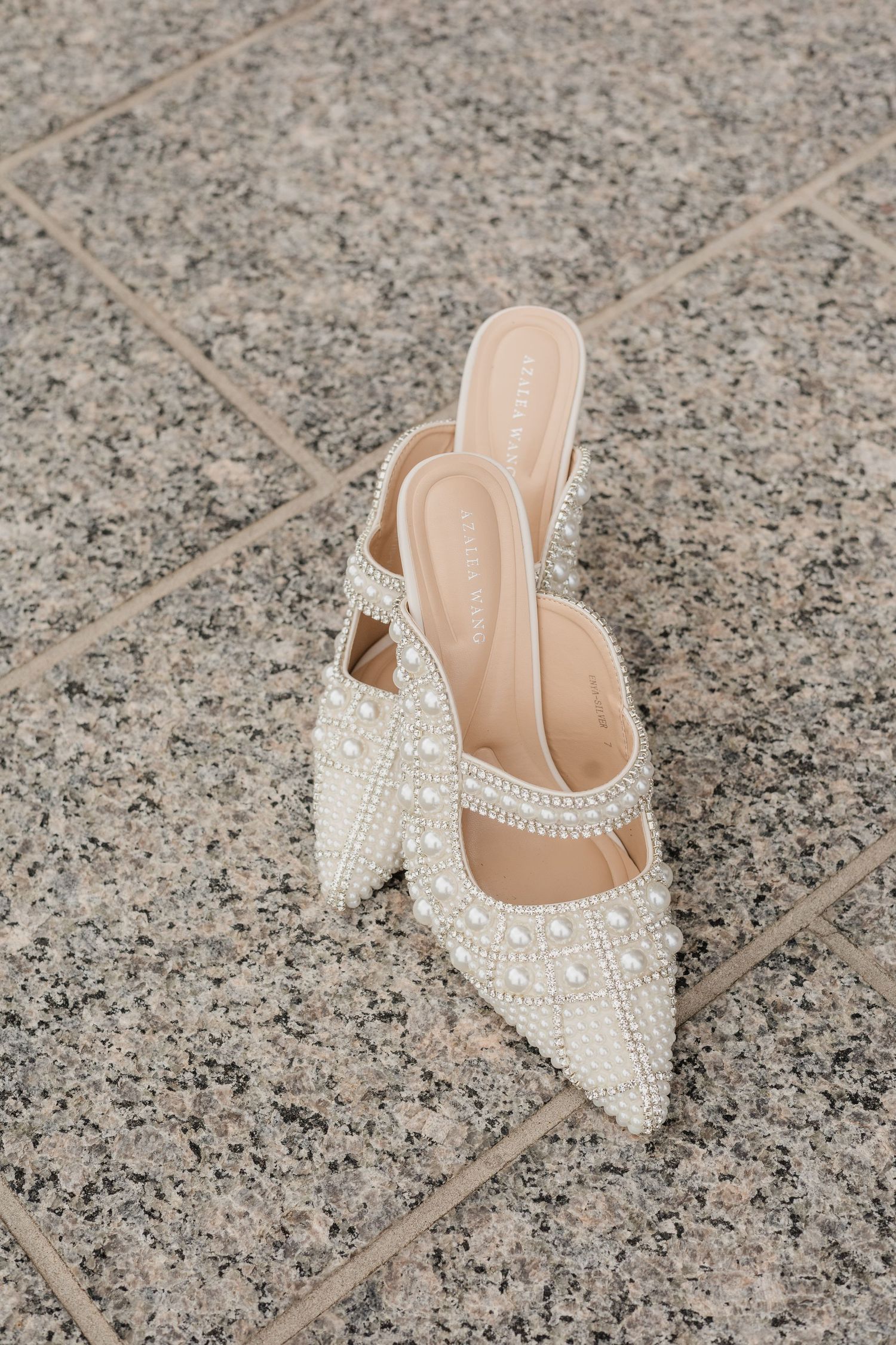 Pearl and crystal embellished pointed toe mule heels on granite tile floor.