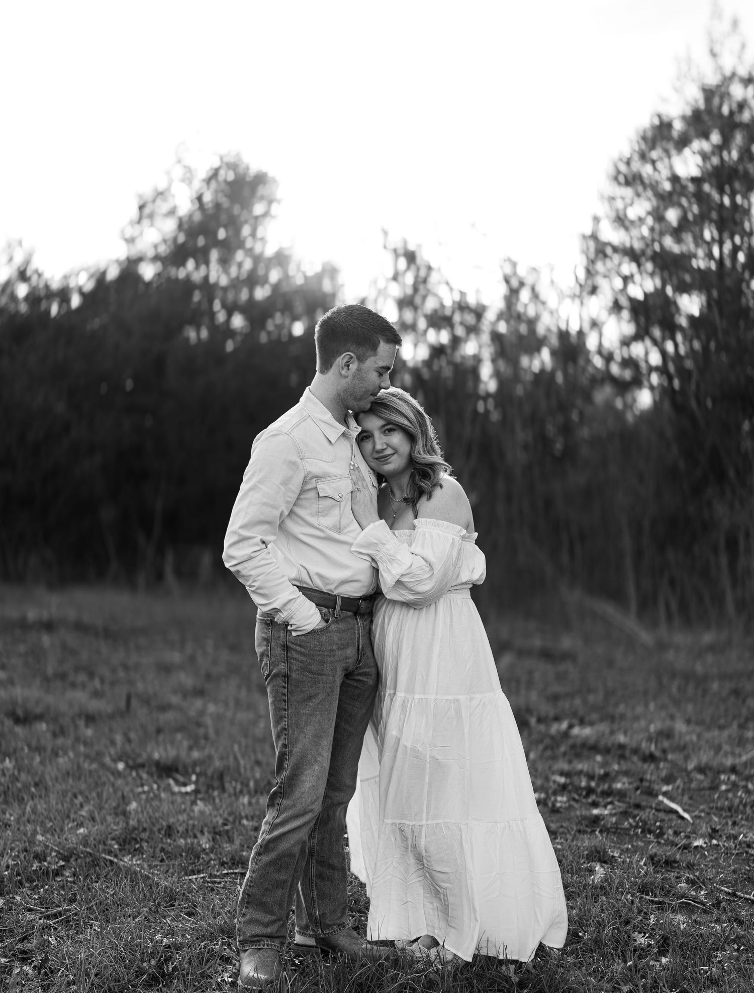 Romantic black and white portrait of a couple embracing in a rustic outdoor setting.