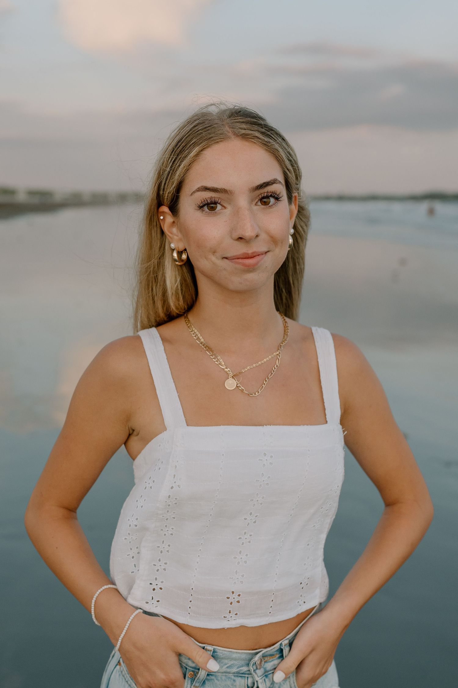 Summer beach portrait with white eyelet crop top and jewelry.
