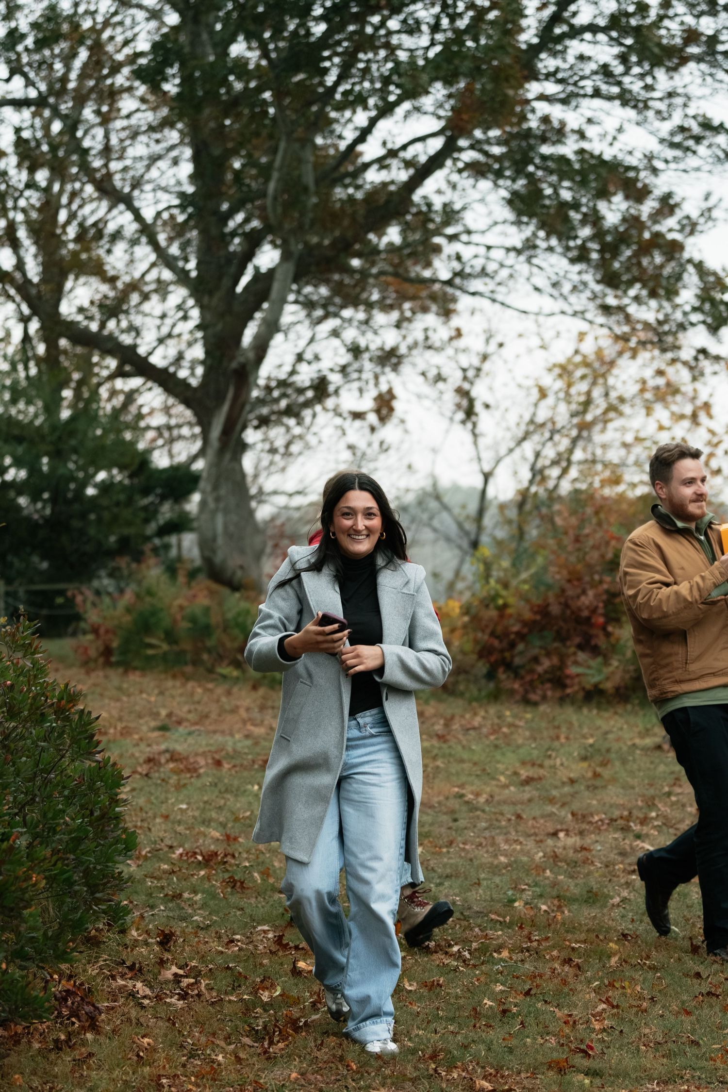 People playing and running through fallen leaves in an autumn park.