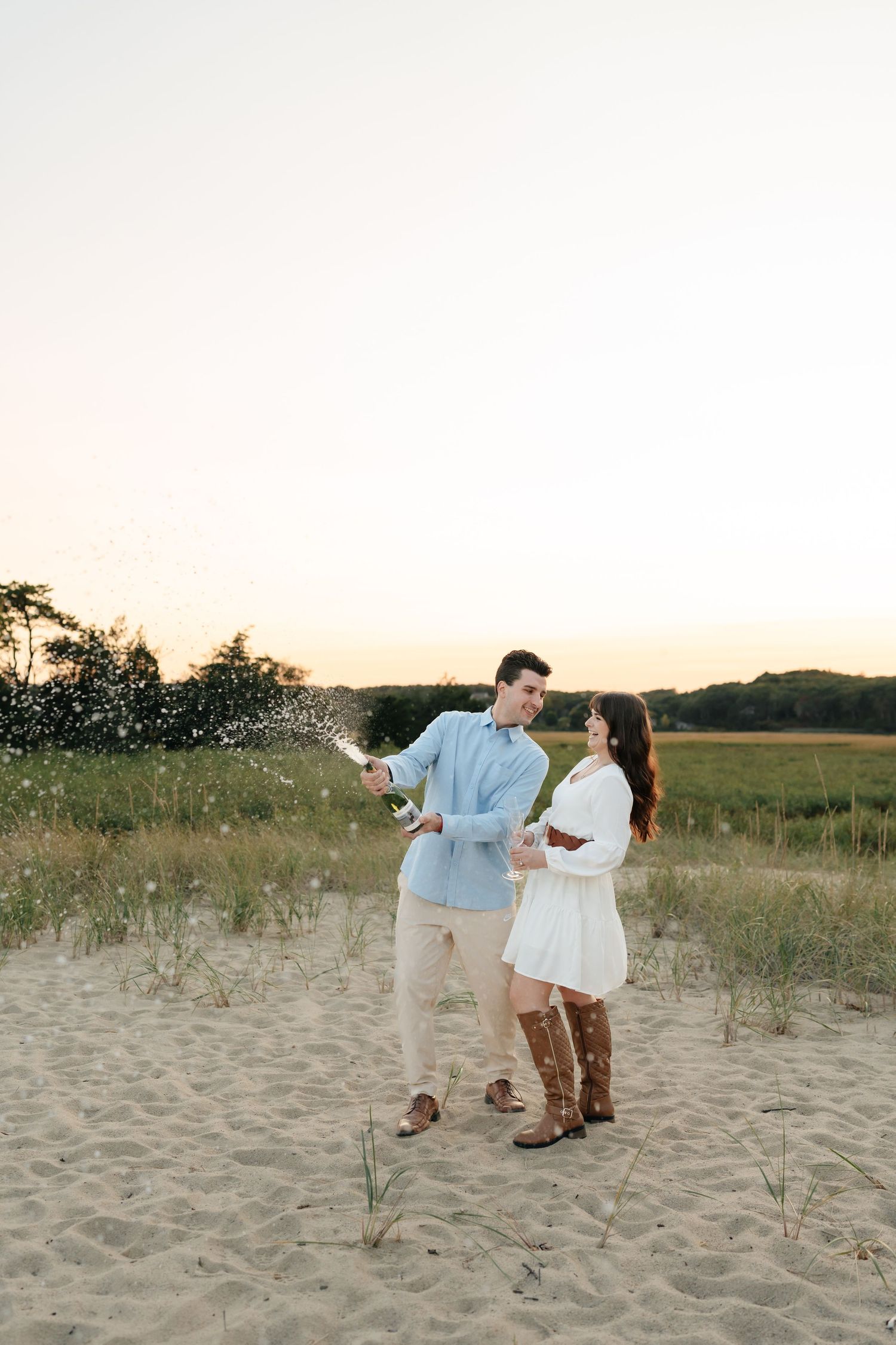 A couple shares a romantic moment on a sandy beach during golden hour.