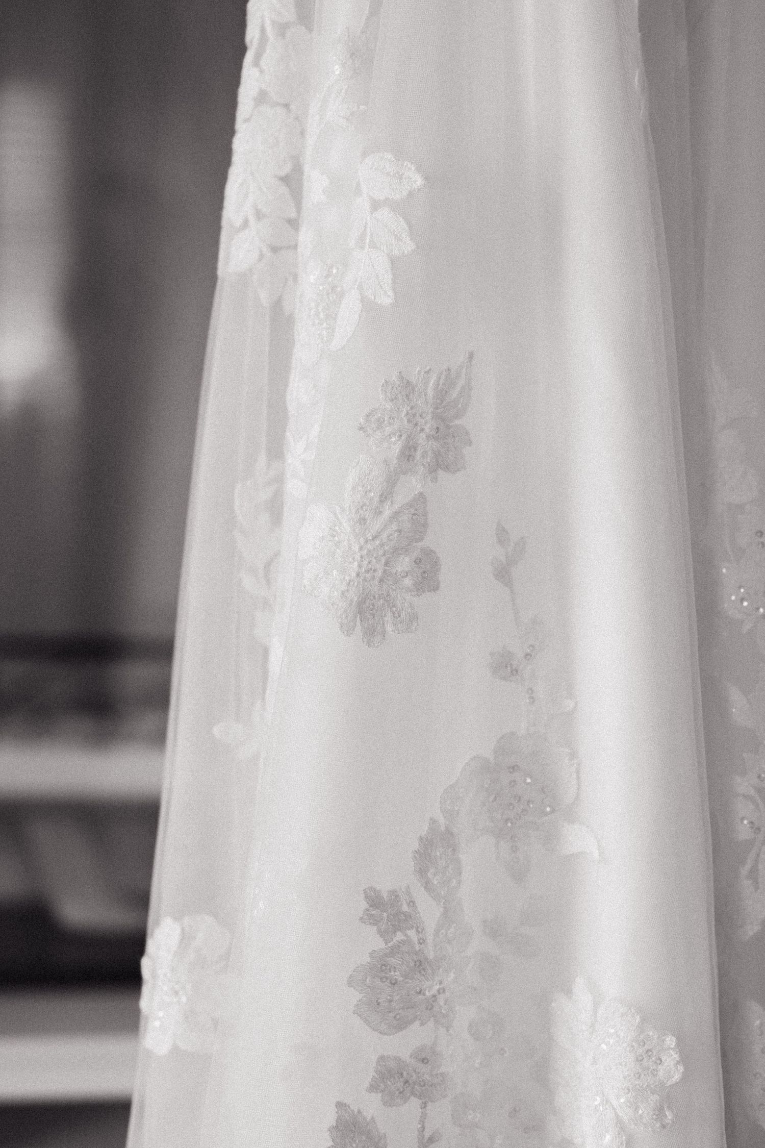 Close-up detail of delicate lace pattern on white wedding dress fabric.