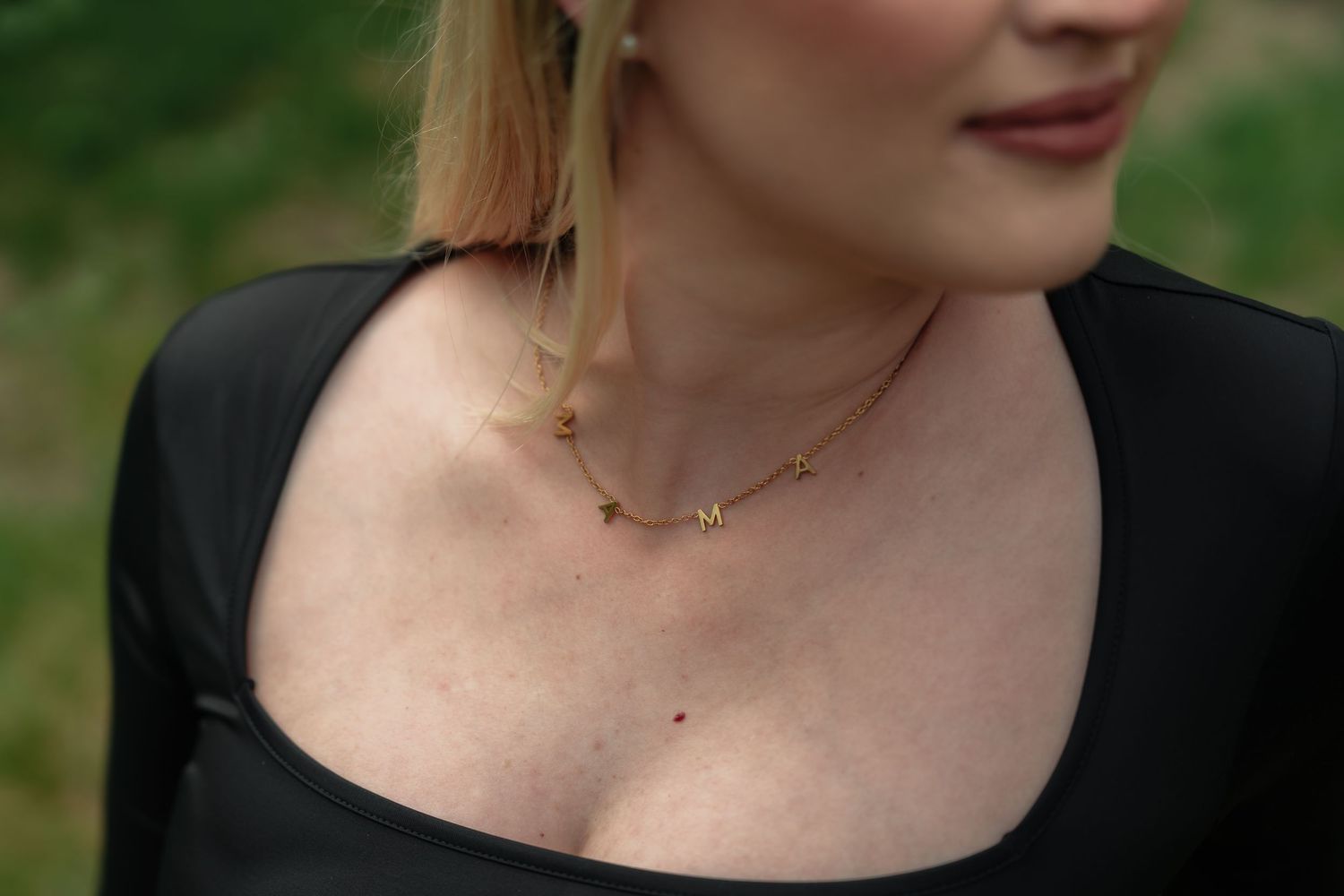 Close-up view of a delicate gold necklace with a minimalist pendant worn against pale skin.