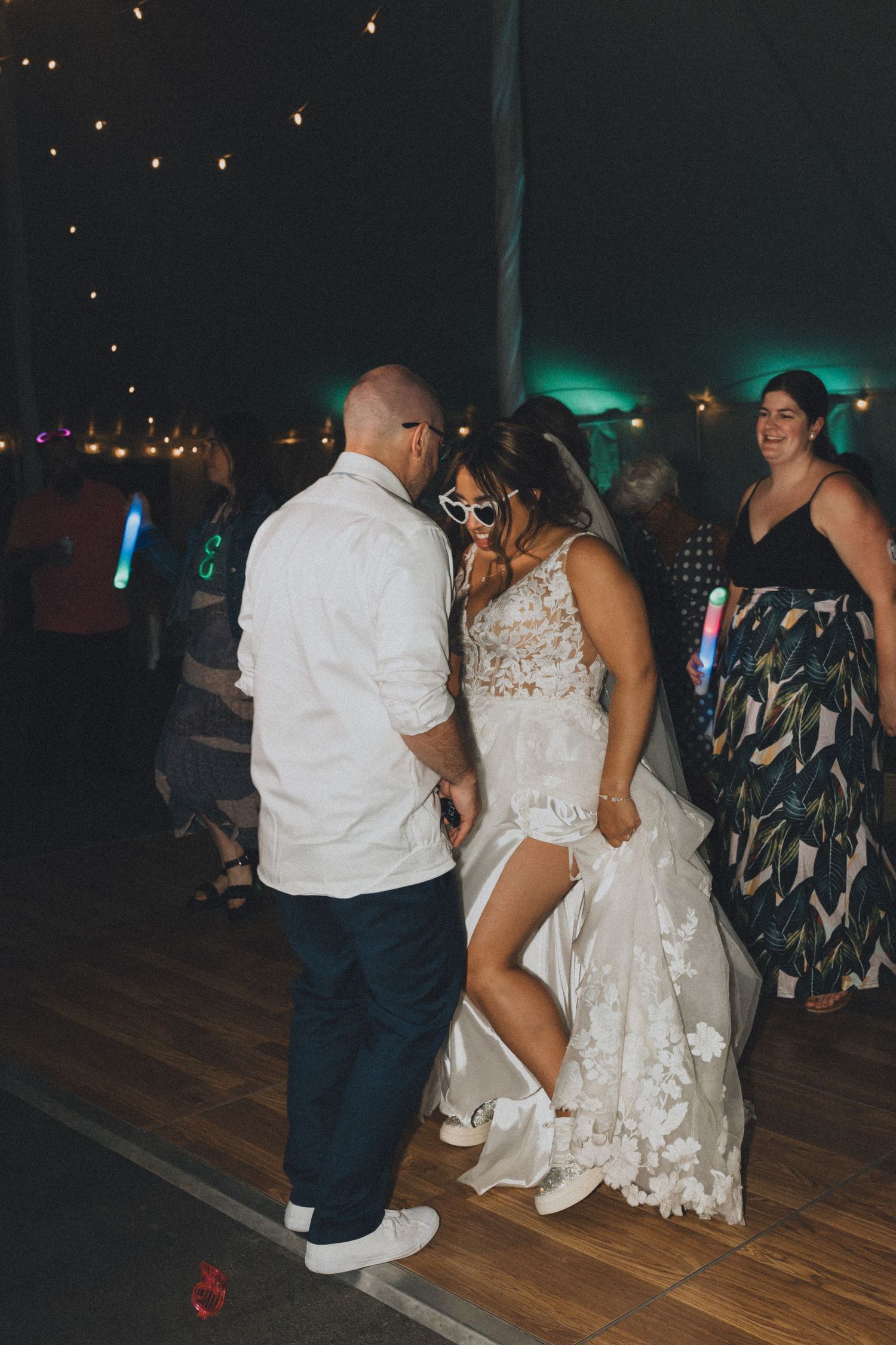 Wedding guests dancing on wooden floor during evening reception.