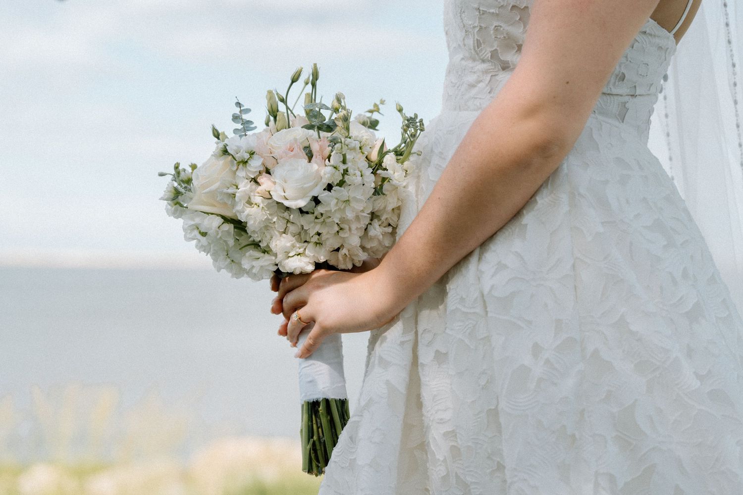 Close-up of bridal bouquet with white flowers against wedding dress.