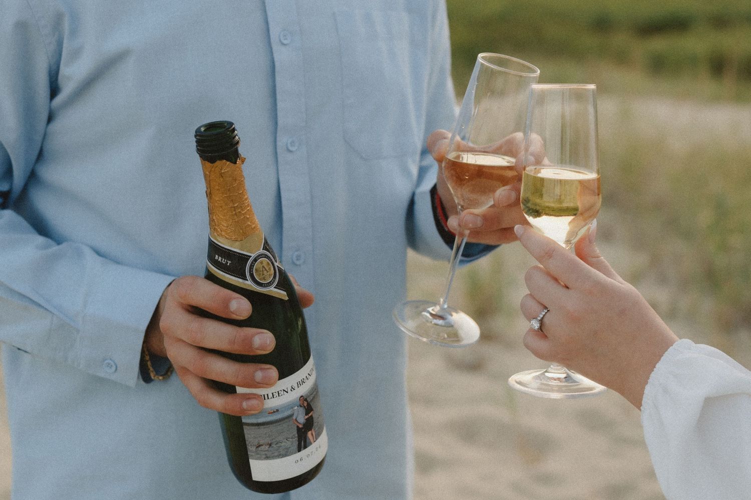 Hands holding champagne glasses and bottles during a beach celebration.