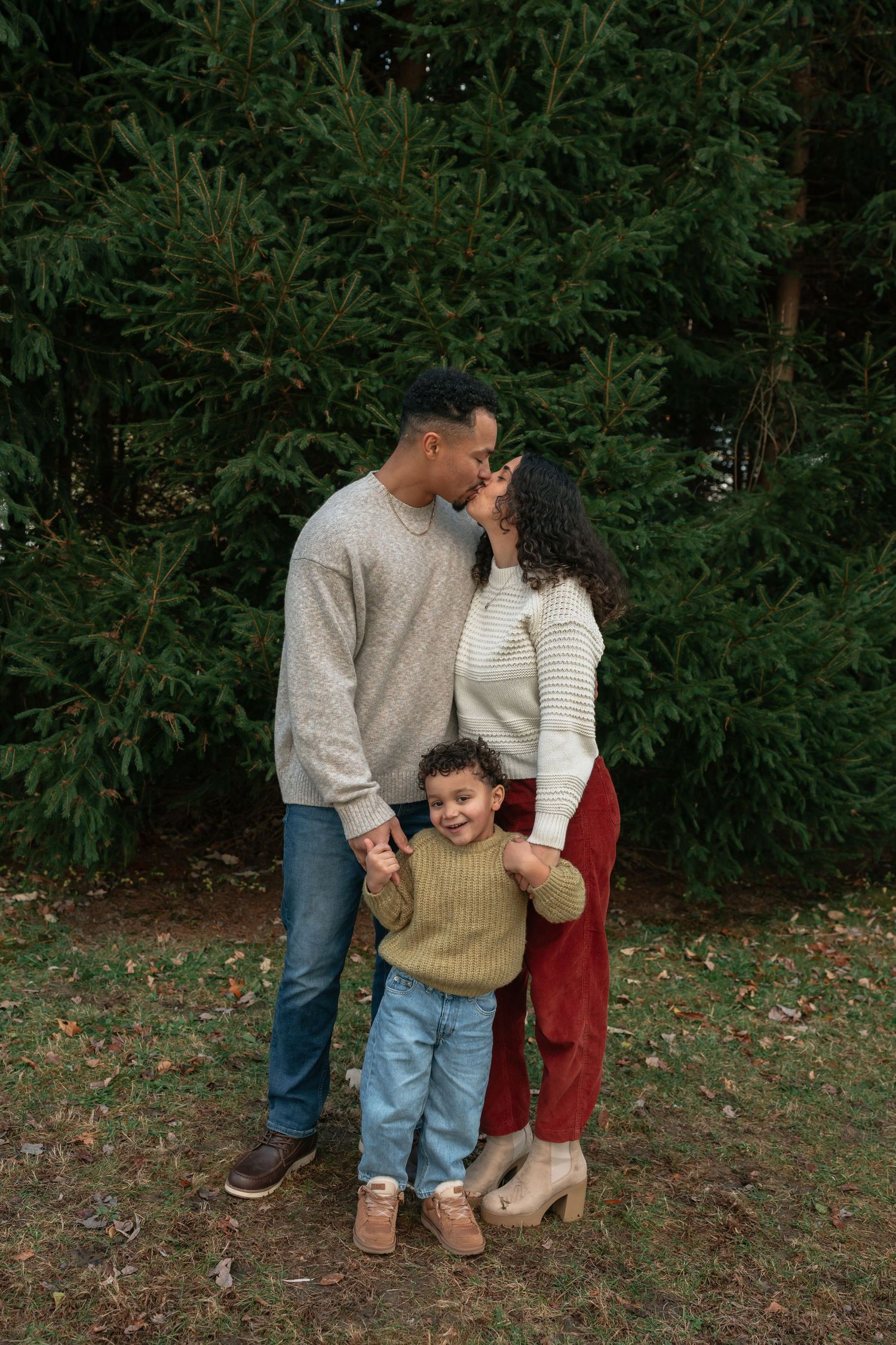 Family sharing intimate moments during outdoor photo session in wooded area.