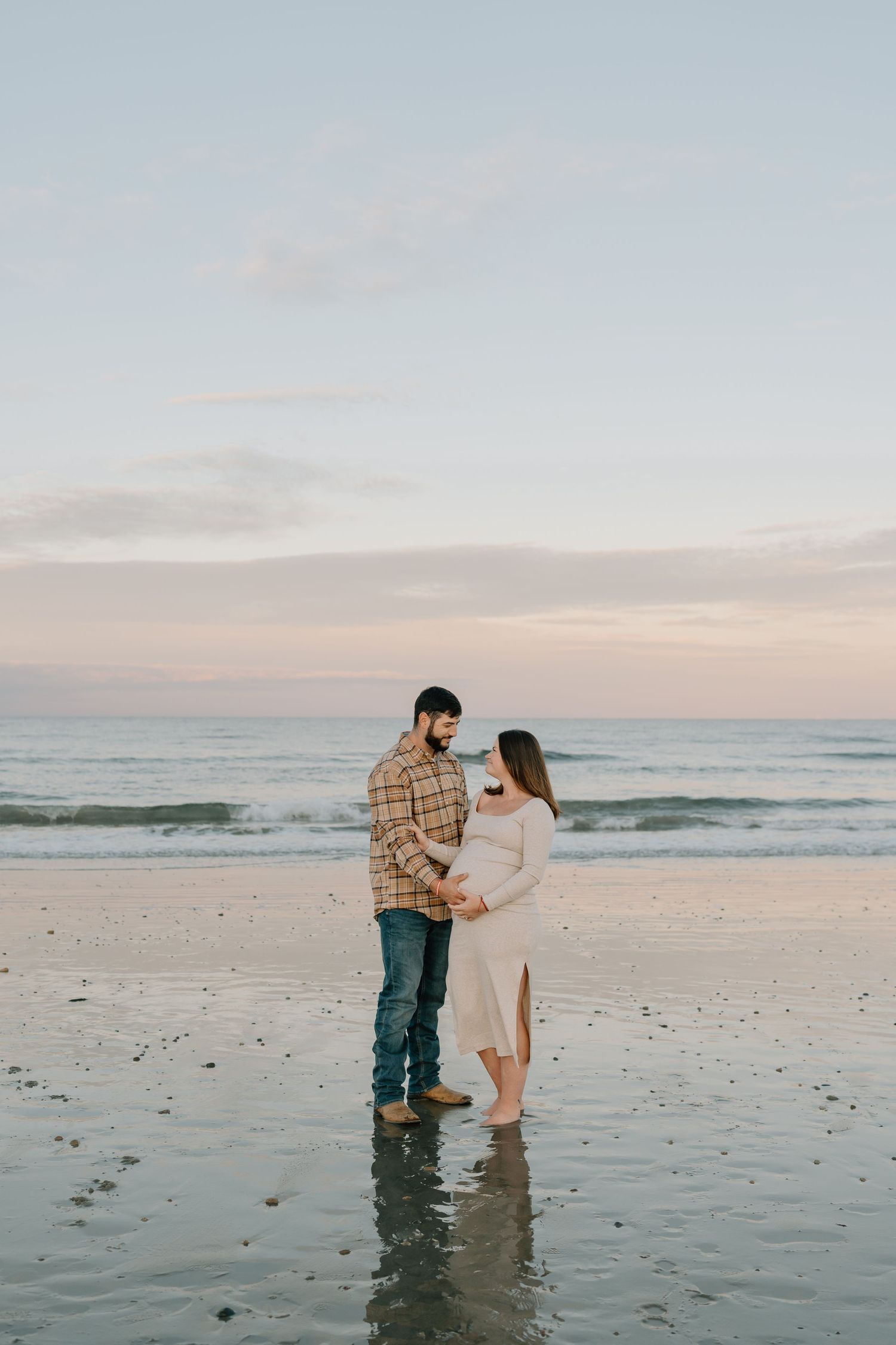 A couple shares a romantic moment on a serene beach during sunset.