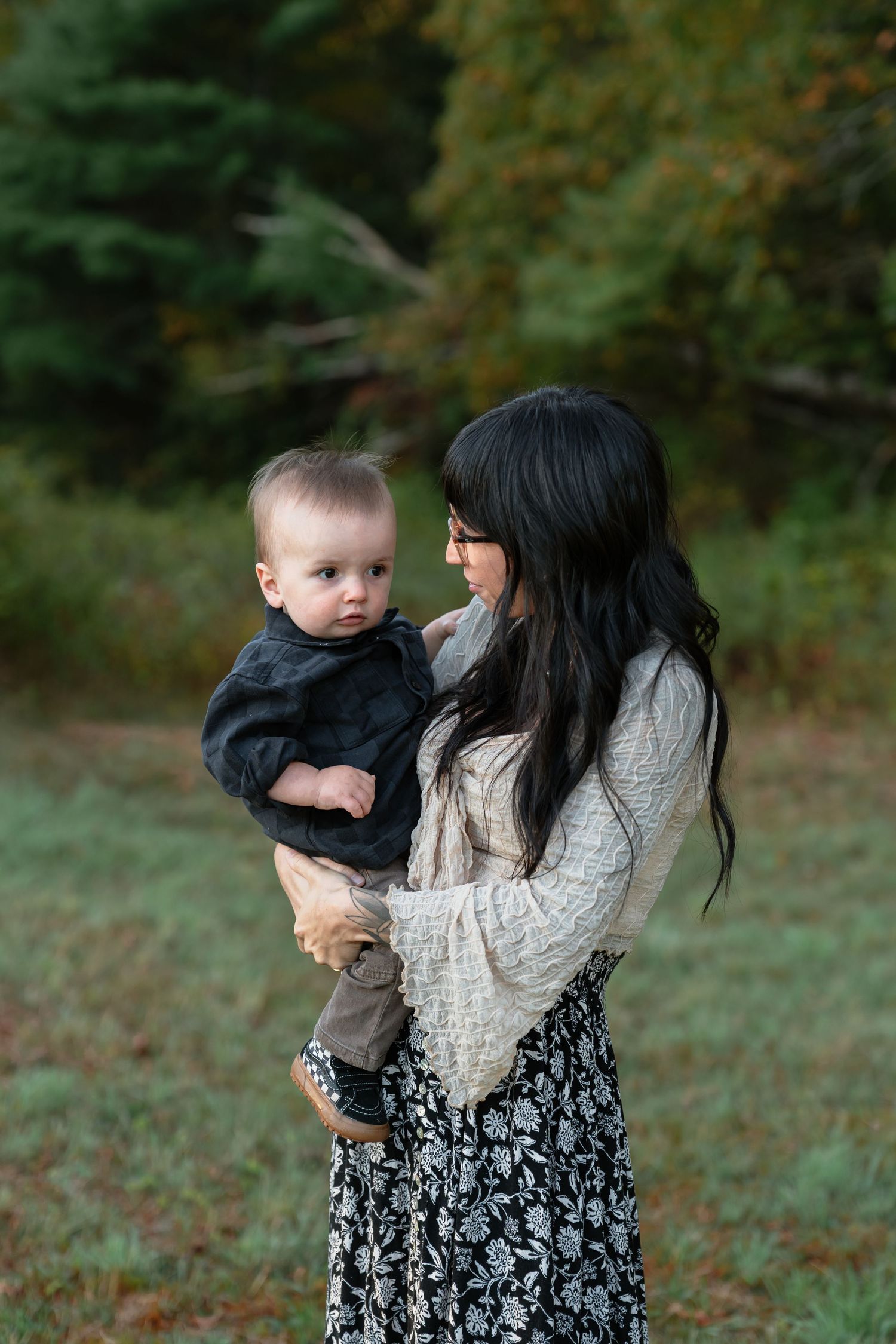 Parent and child share an intimate moment outdoors in fall setting.