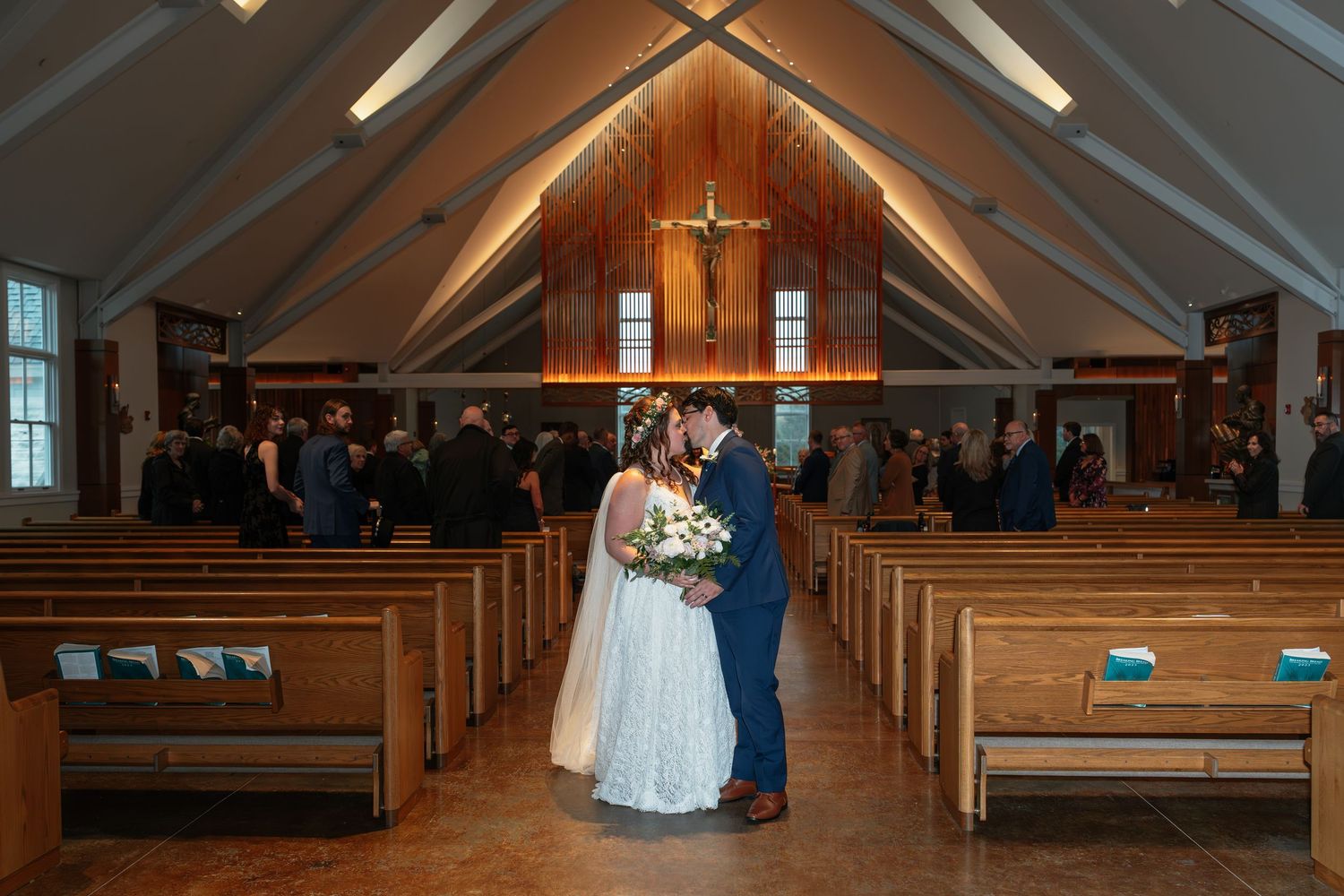 Church sanctuary with wooden pews and vaulted ceiling during a wedding ceremony.