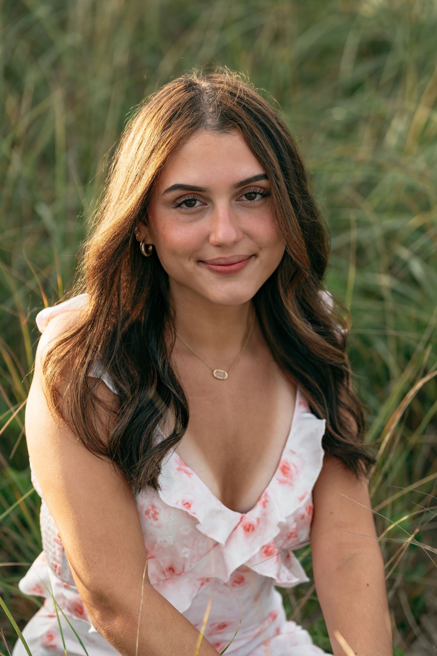 A person in a ruffled white dress sits in a field of tall grass.