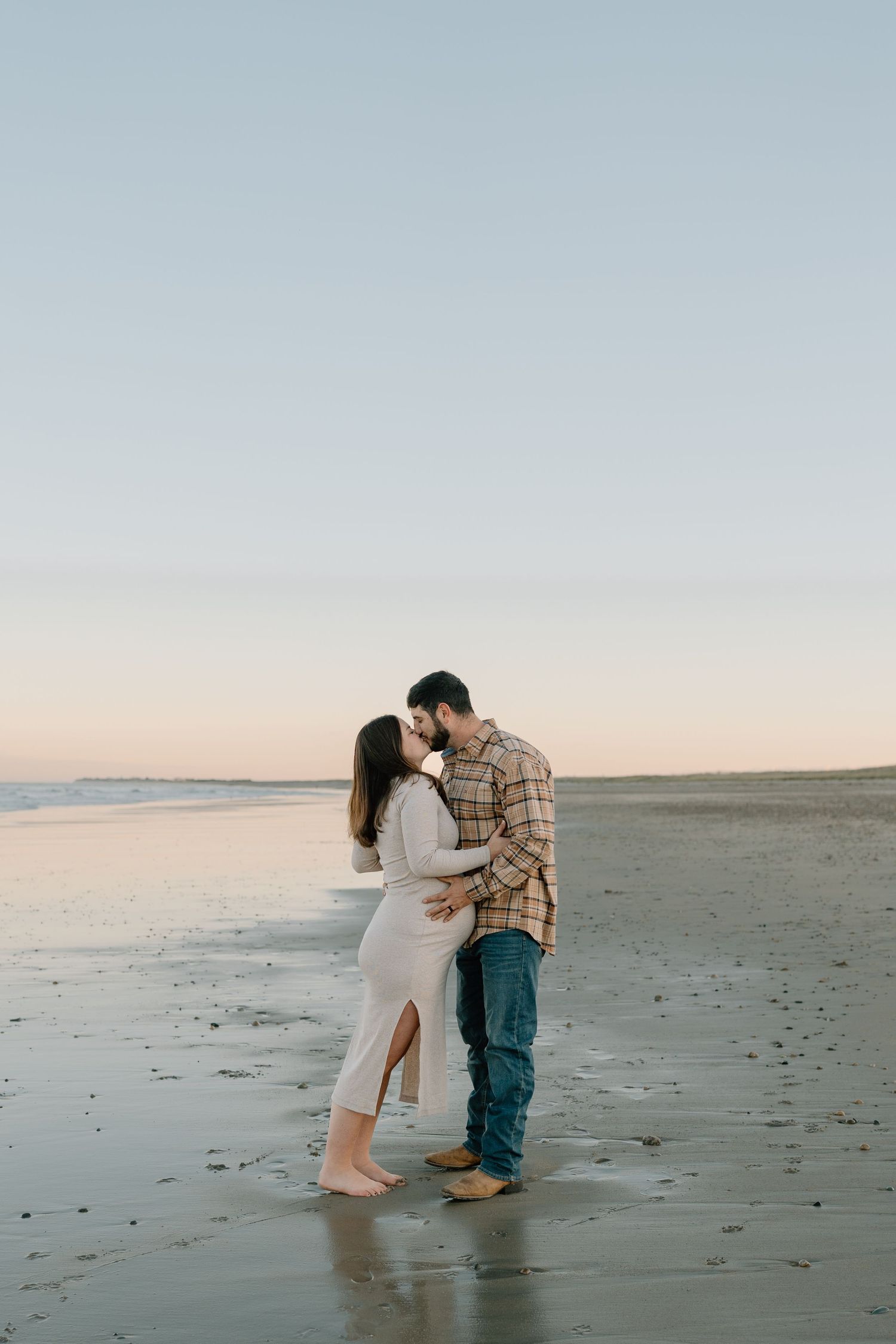 A couple shares an intimate moment on the beach during sunset.