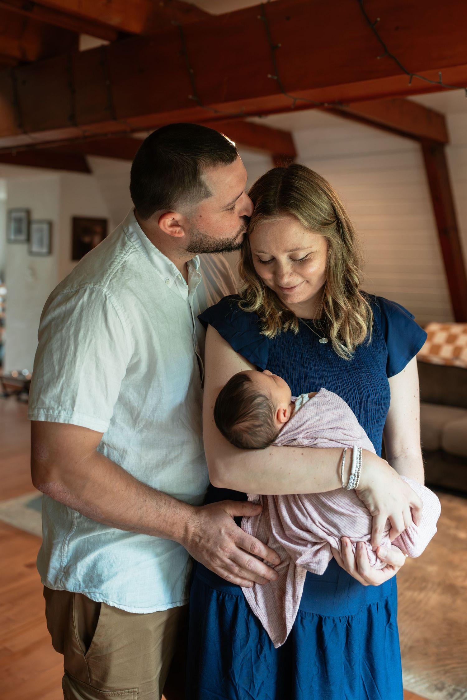 Parents sharing tender moments with their newborn baby in a rustic indoor setting.