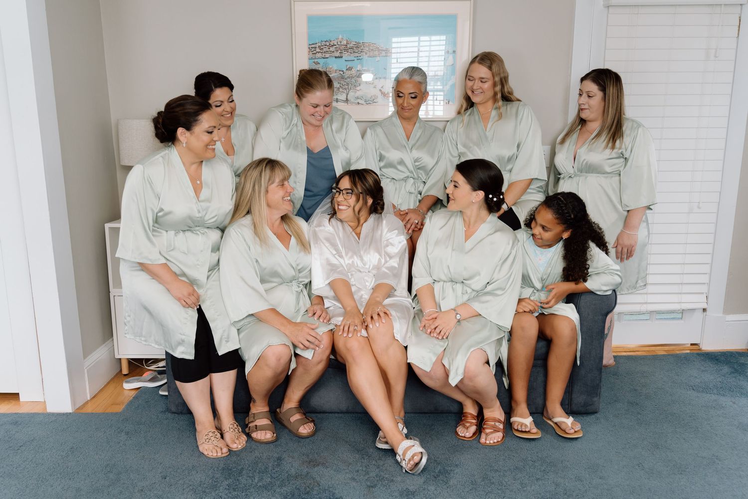 Bridal party in matching robes sitting together during wedding preparations.