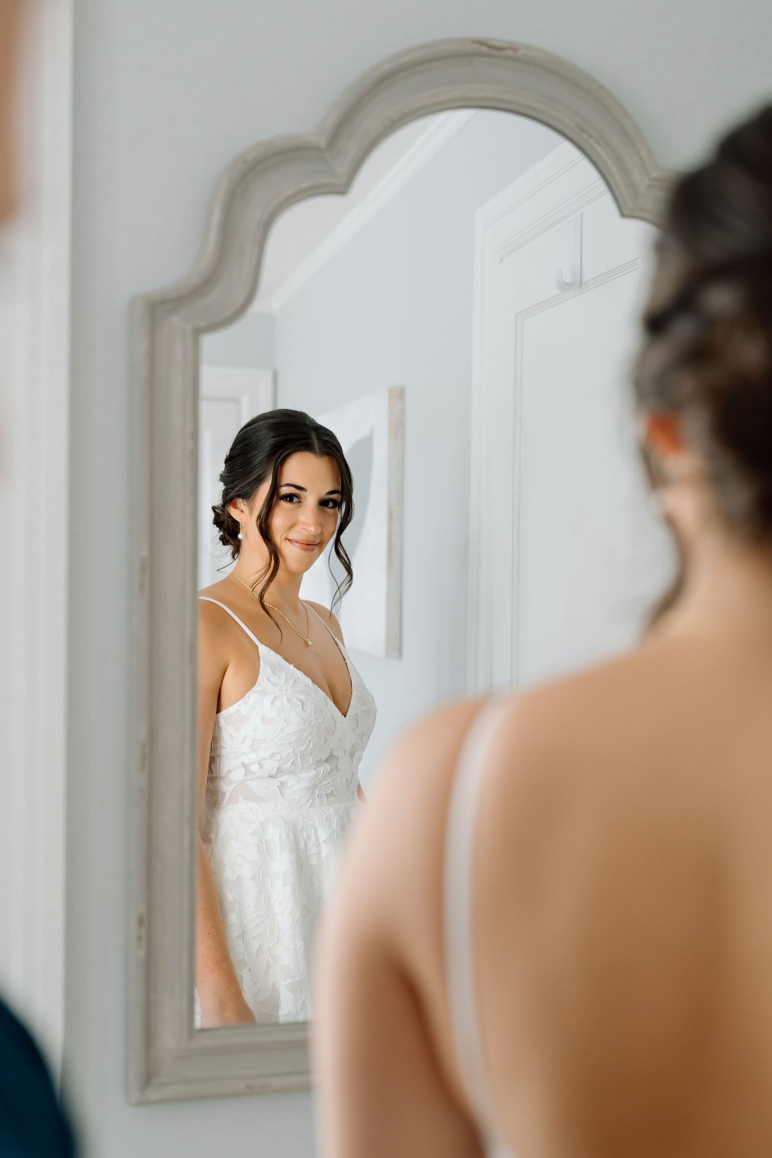 Elegant bridal portrait reflected in ornate white framed mirror.